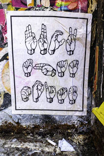 Hands forming american sign language alphabet on poster.