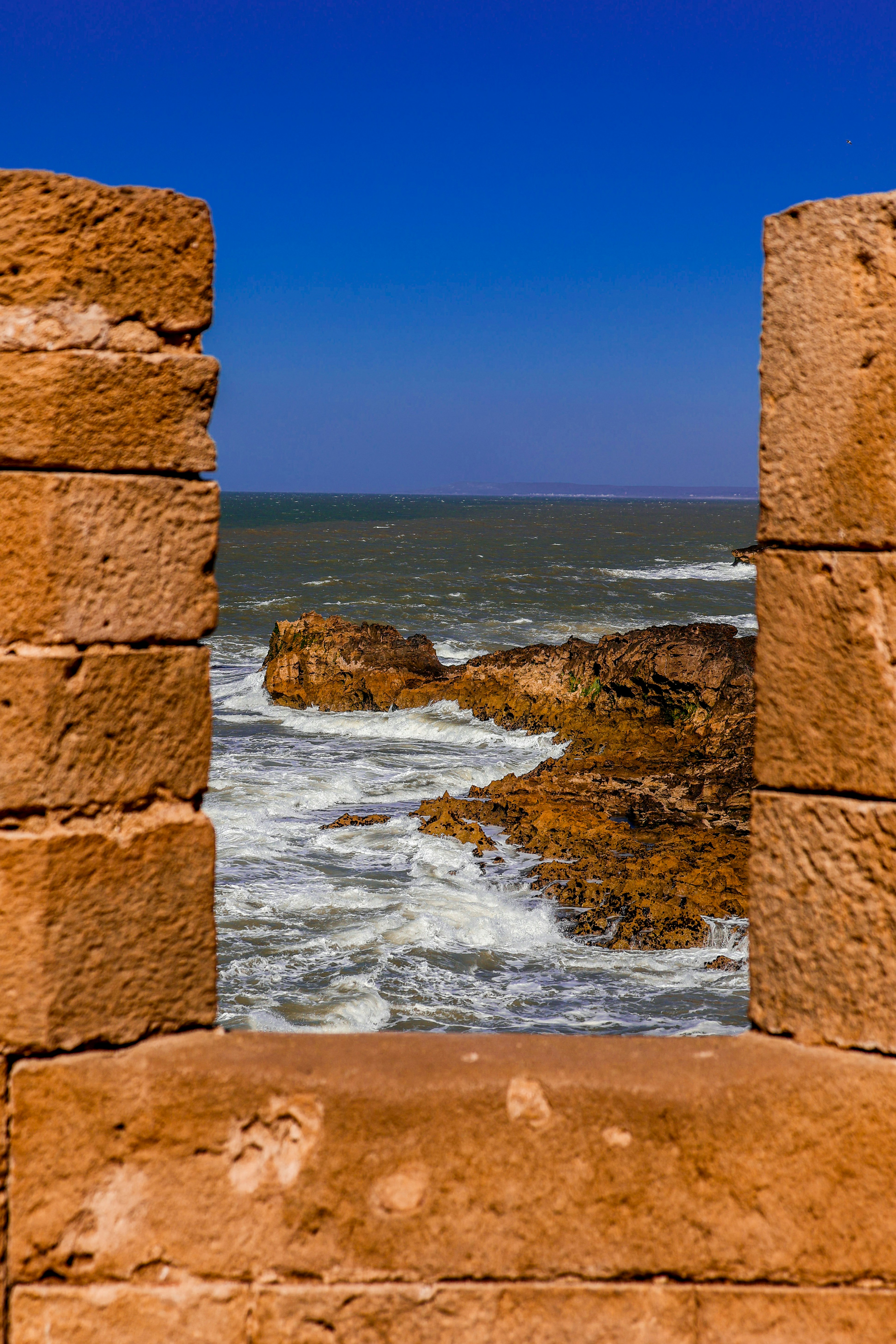 Les vagues de l’océan s’écrasent contre le rivage rocheux à travers la fenêtre de pierre