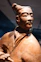 Terracotta warrior statue with traditional hairstyle and historical clothing.