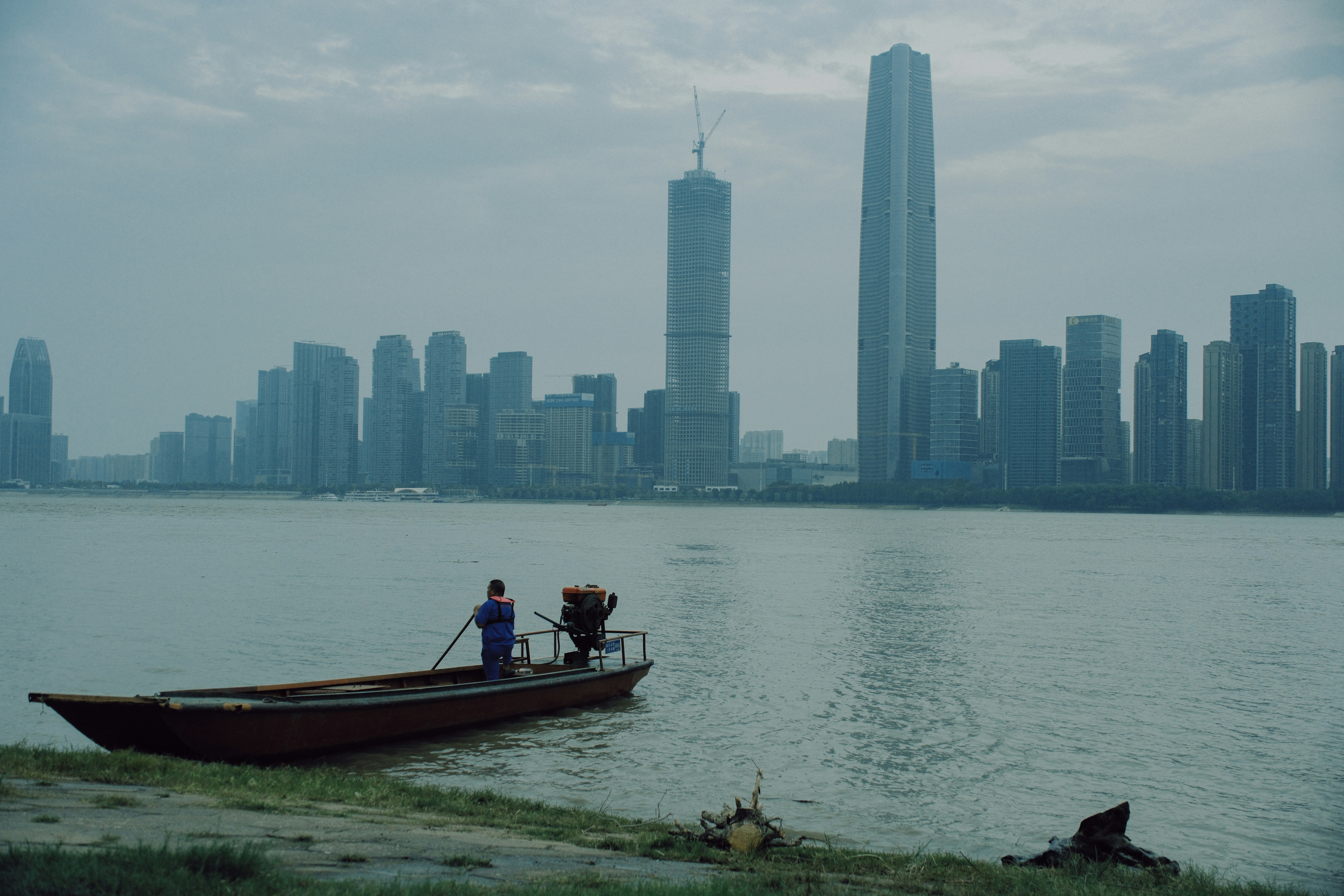 Perahu tunggal di atas air dengan cakrawala kota.