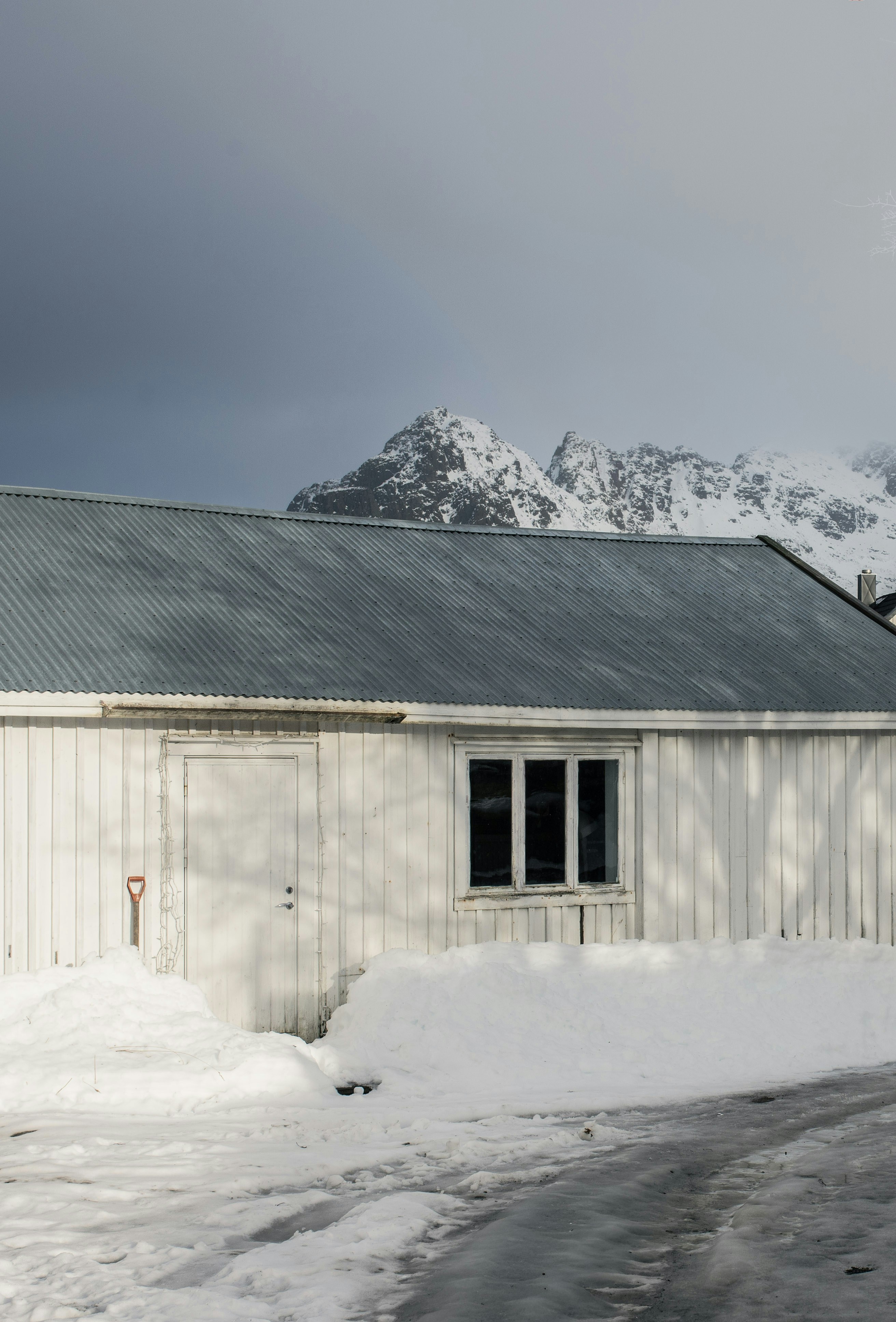 Edificio de madera blanca en la nieve con montañas detrás