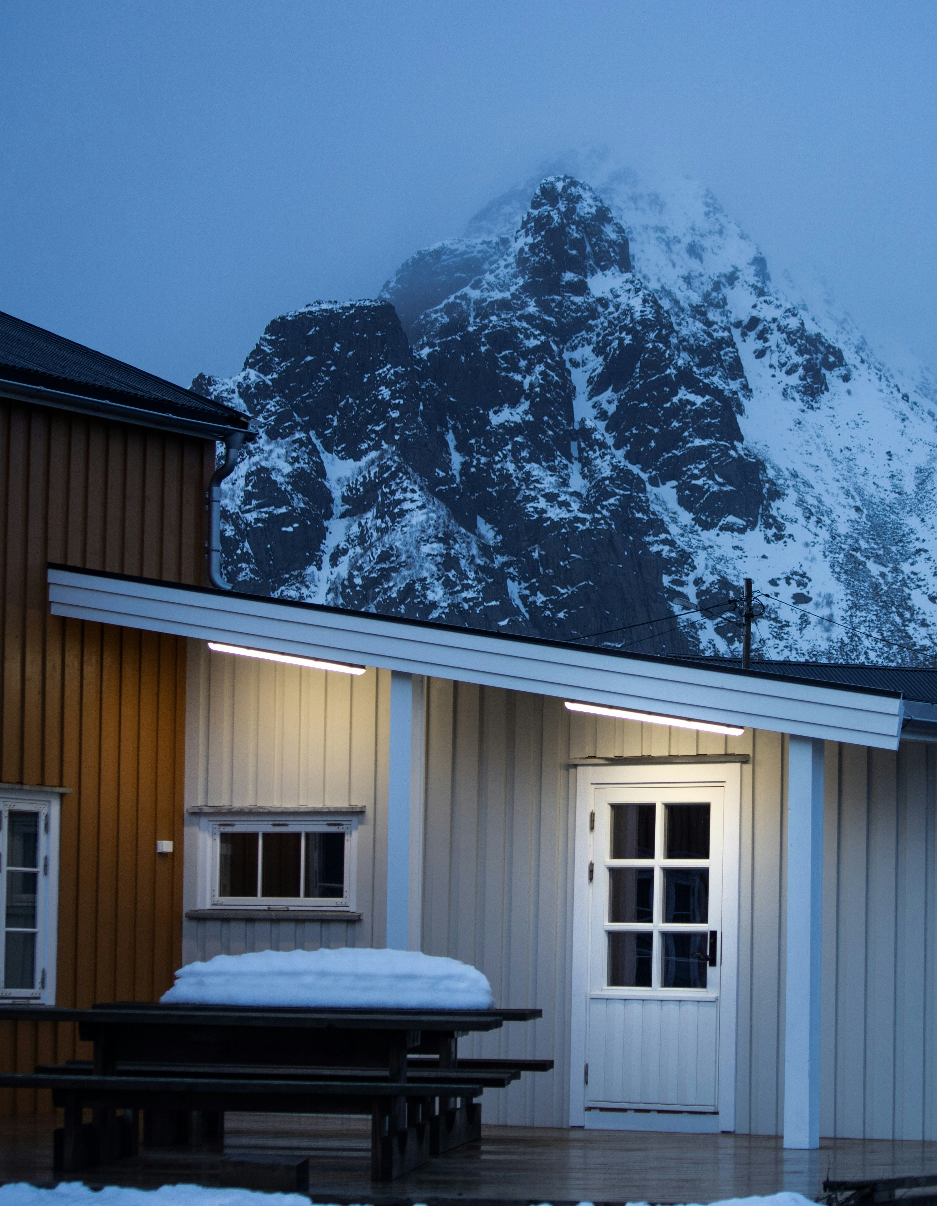 Una cabaña de madera con una montaña cubierta de nieve detrás.