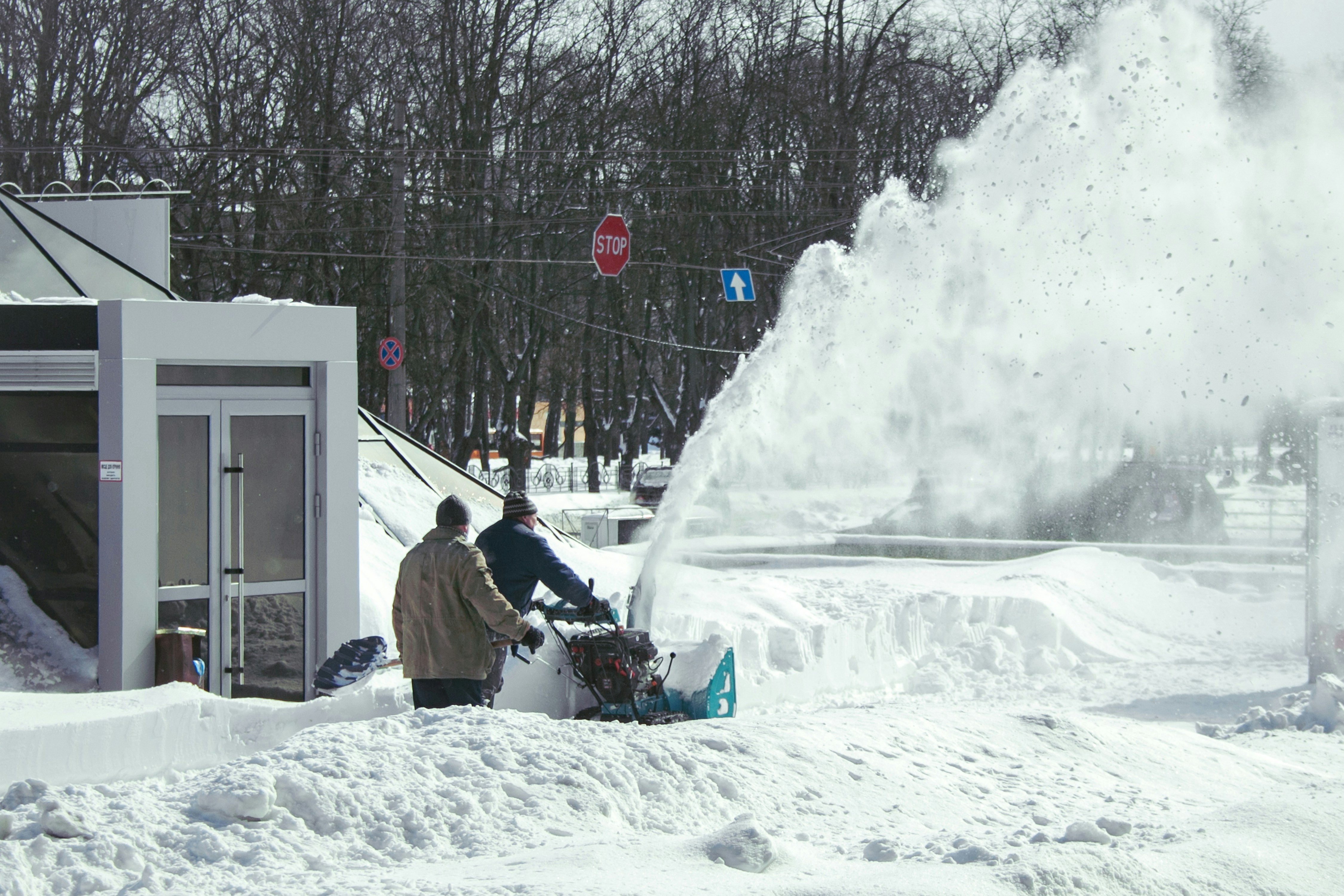 Two people operating a snowblower clearing a snowy path