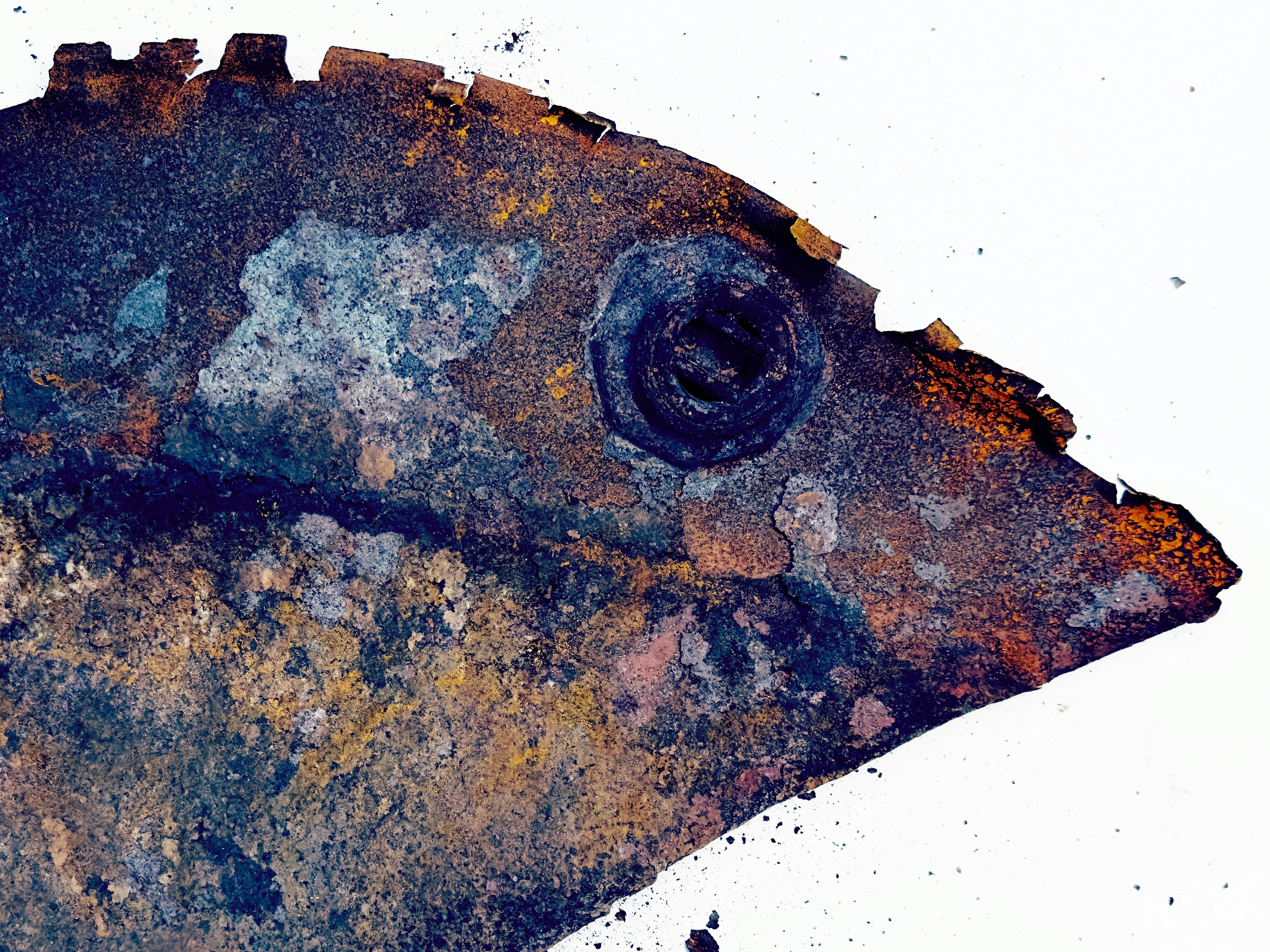 Close-up benda logam berkarat dengan lekukan melingkar.