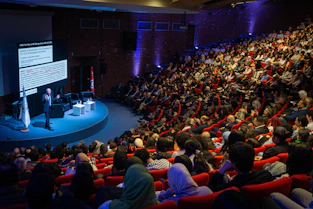 Speaker presenting to large audience in auditorium
