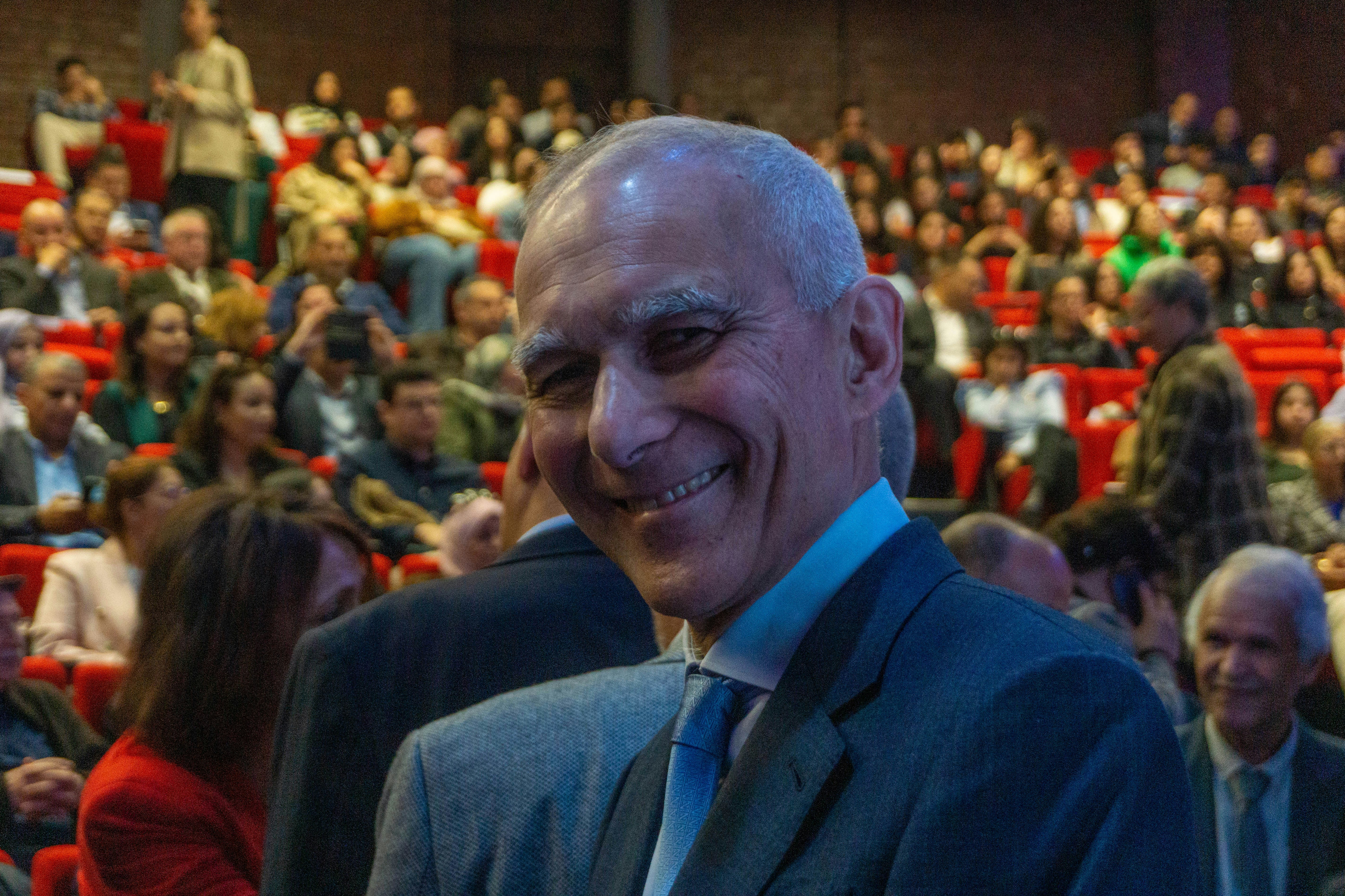 Smiling man in suit with audience in background