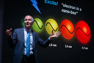 Man presenting science with colorful spheres on screen
