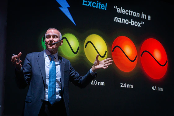 Man presenting science with colorful spheres on screen
