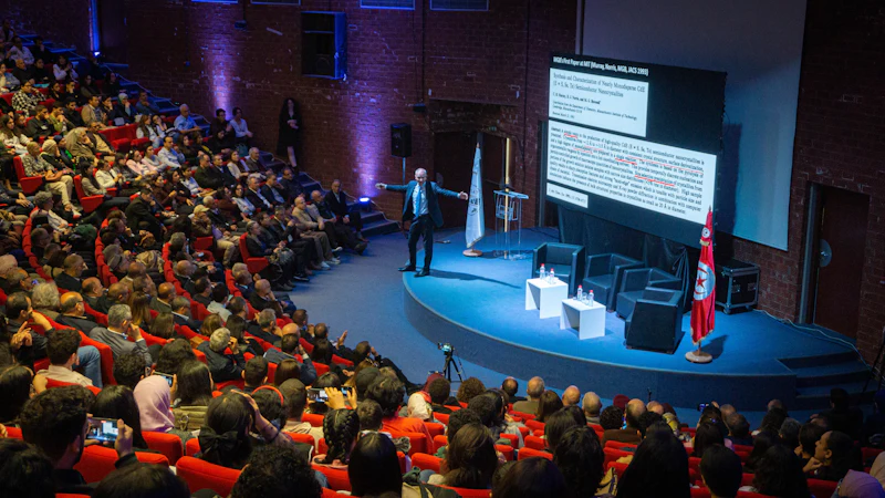 A packed auditorium facing a speaker on stage