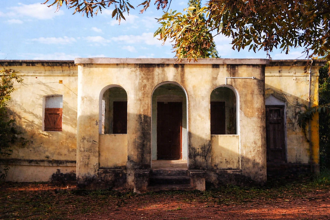 A weathered Indian house with arched doorways and windows.