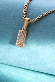 A gold pendant with diamonds on a chain.