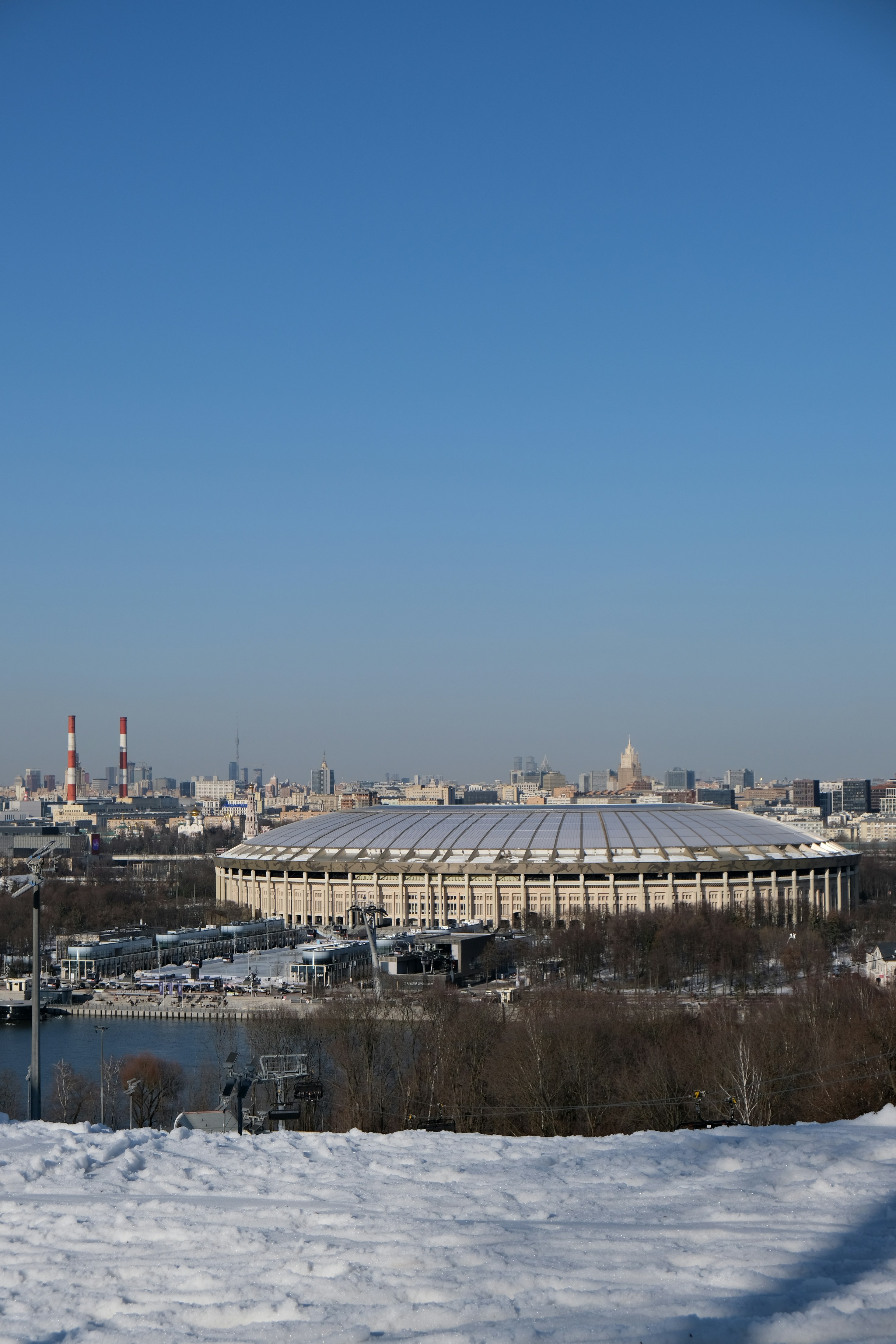 Large stadium complex surrounded by city buildings under clear sky