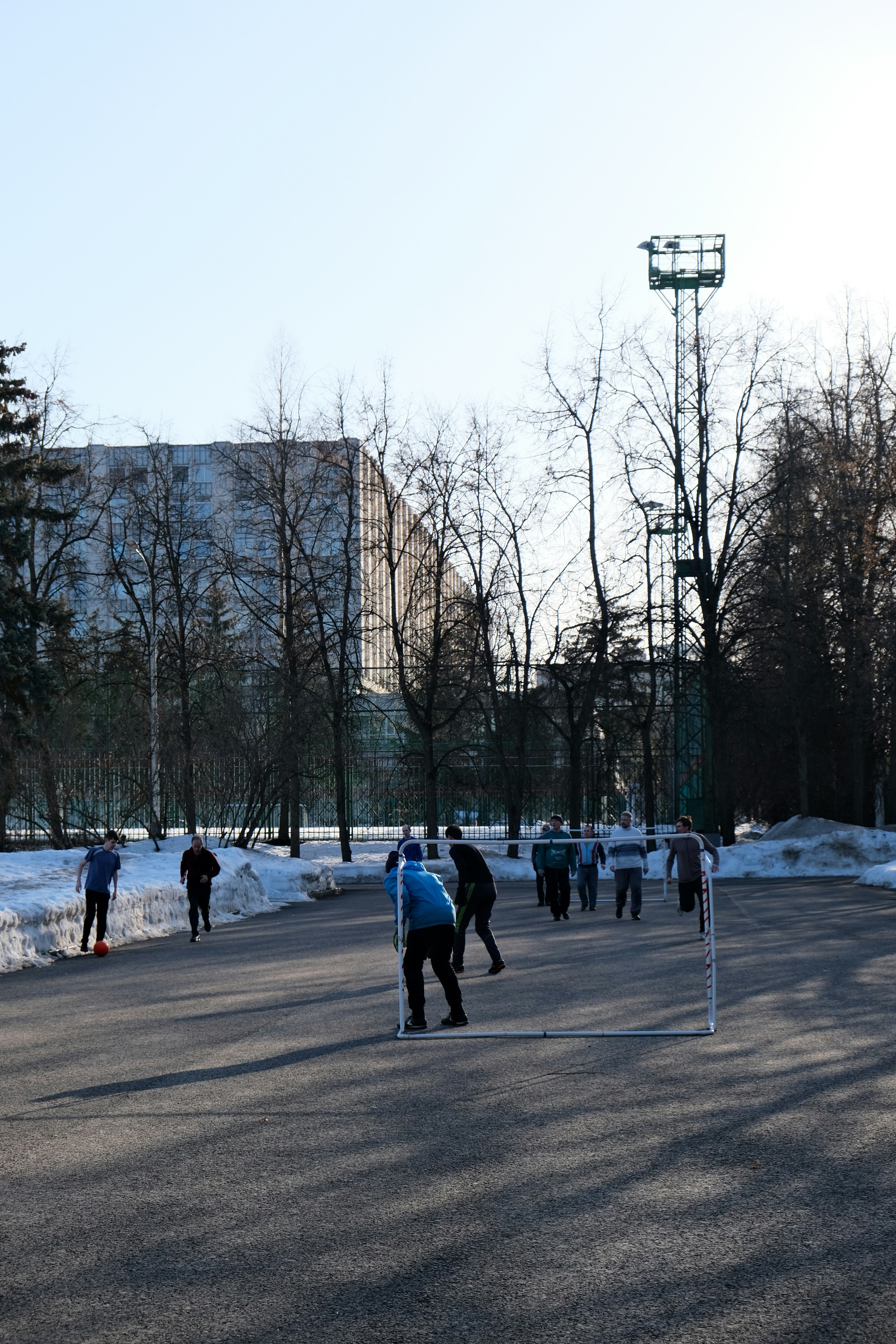 People playing hockey on an outdoor rink in winter.