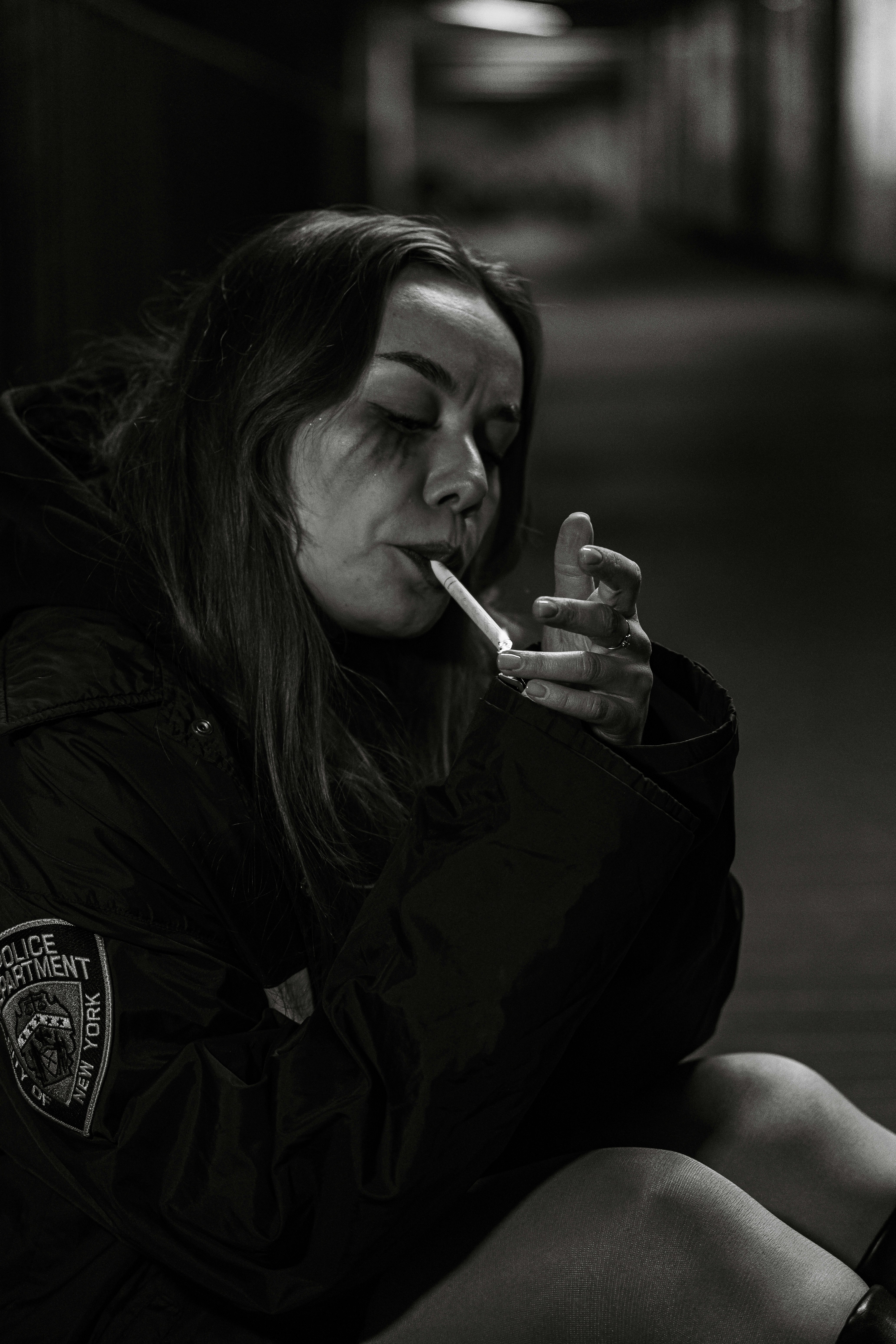 Woman lighting a cigarette in a dark hallway.
