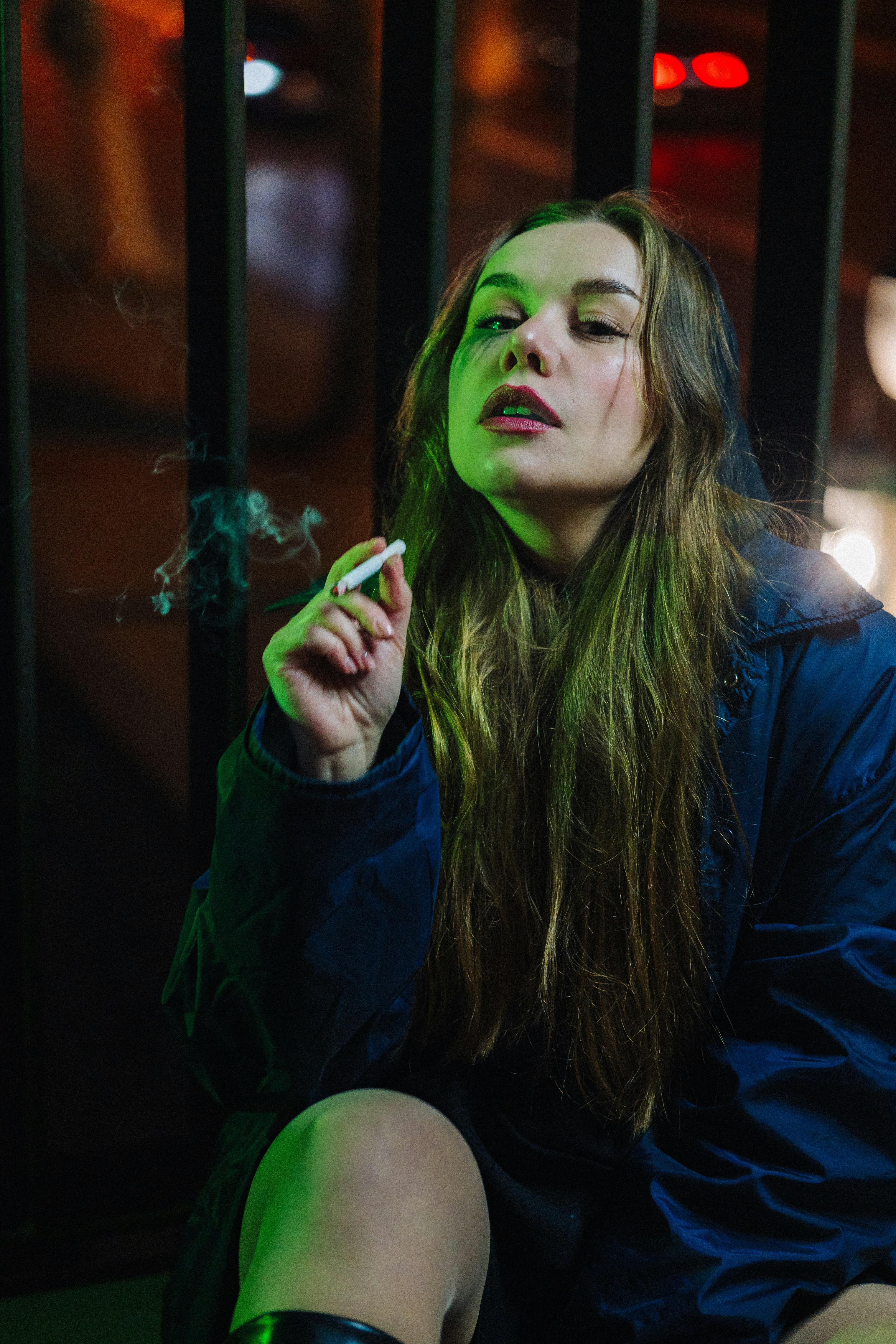 Young woman smoking a cigarette at night with neon lights