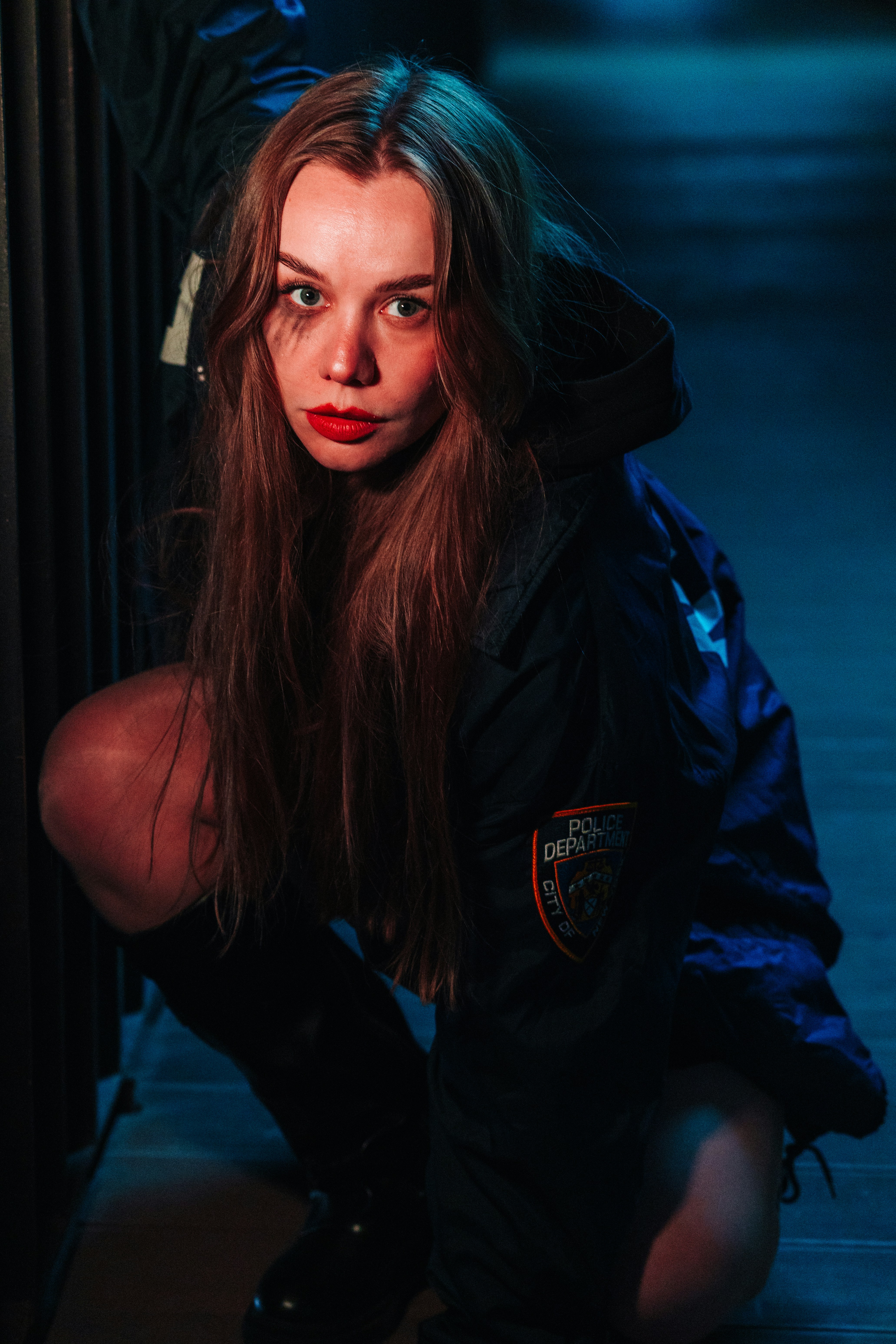 Woman in dark jacket with red lipstick crouching