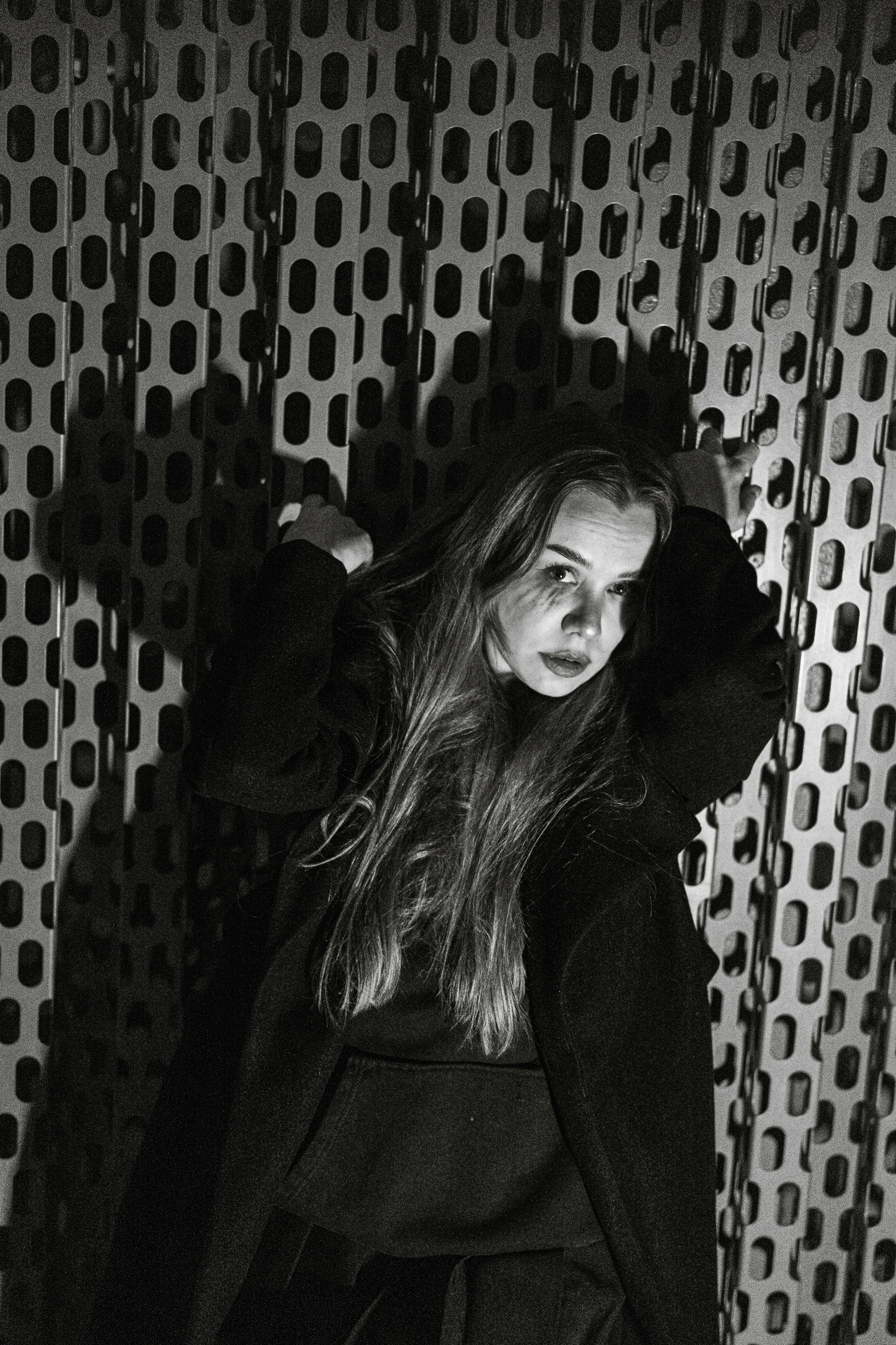 Young woman with long hair standing against patterned wall