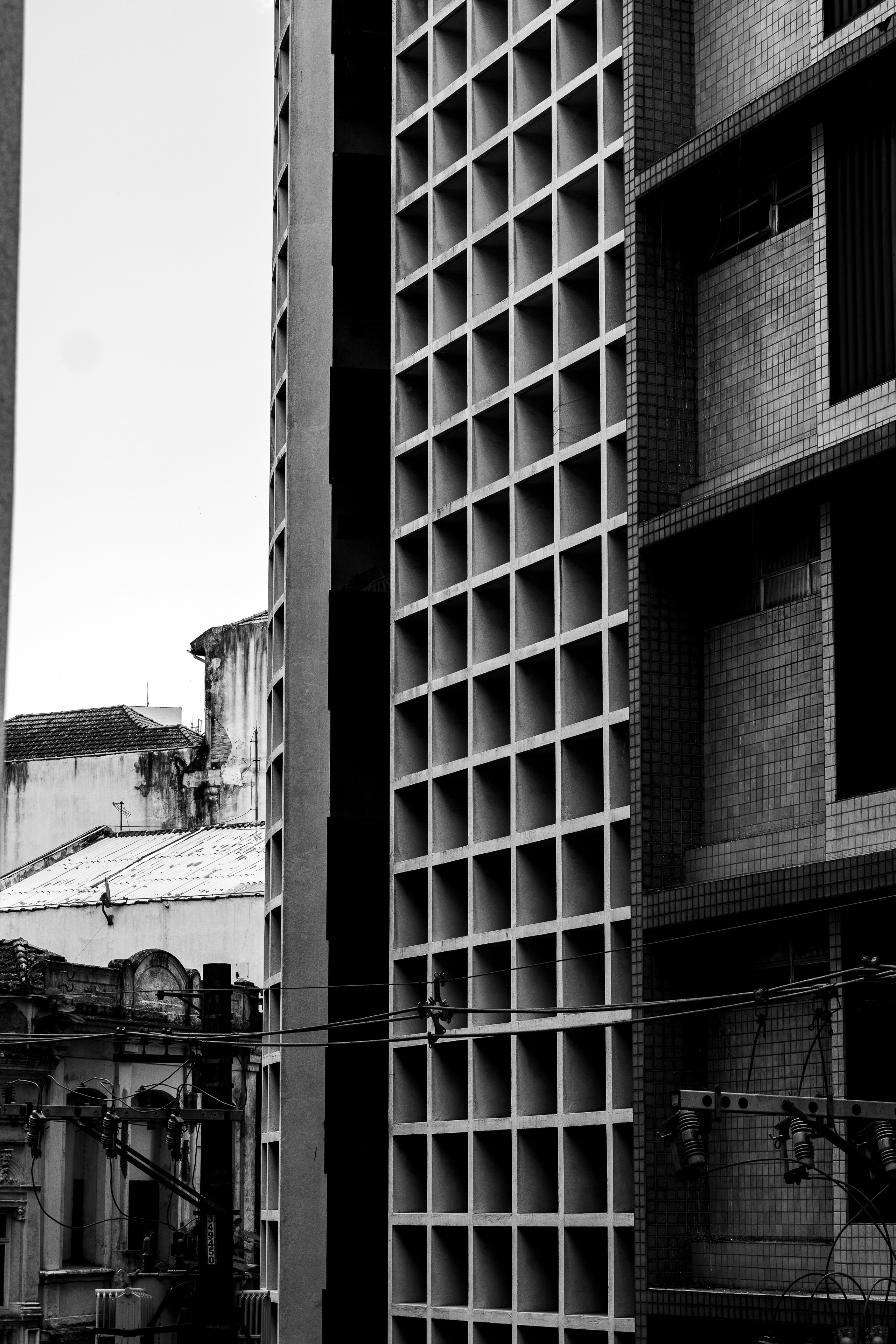 Urban geometry: stark concrete grids contrast with weathered buildings and tangled wires.