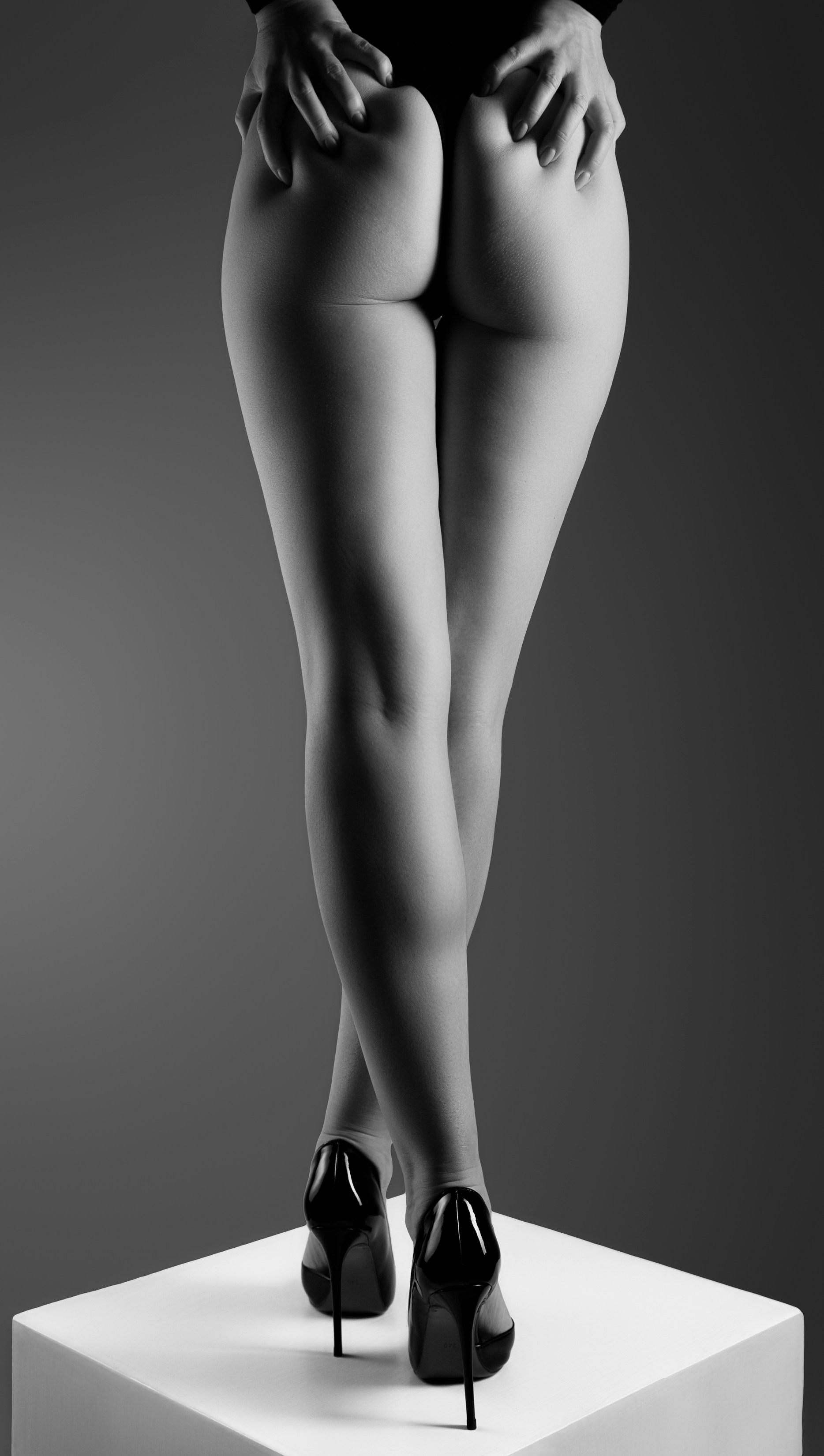 Woman in high heels standing on a white cube.