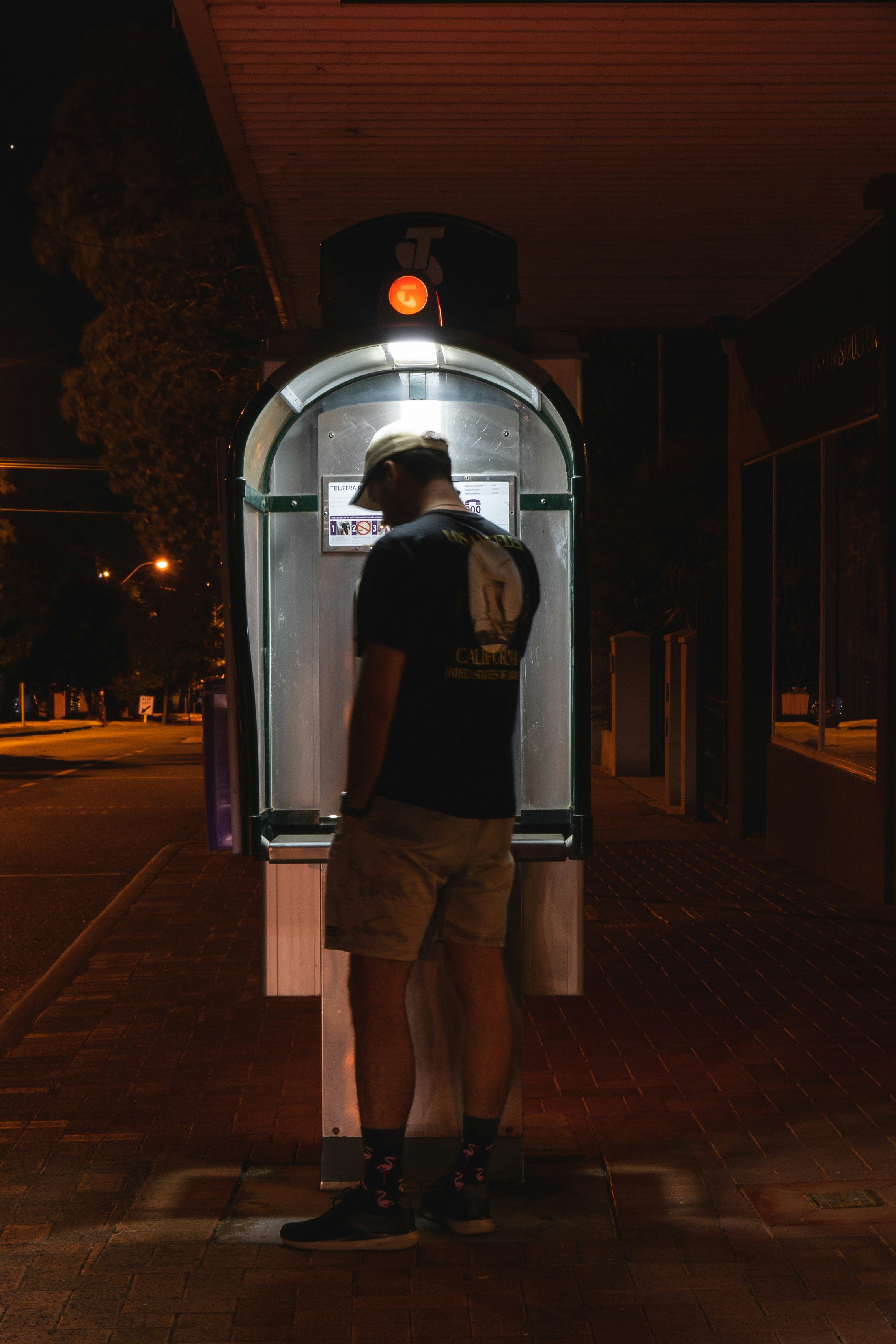 Man standing at a brightly lit kiosk at night
