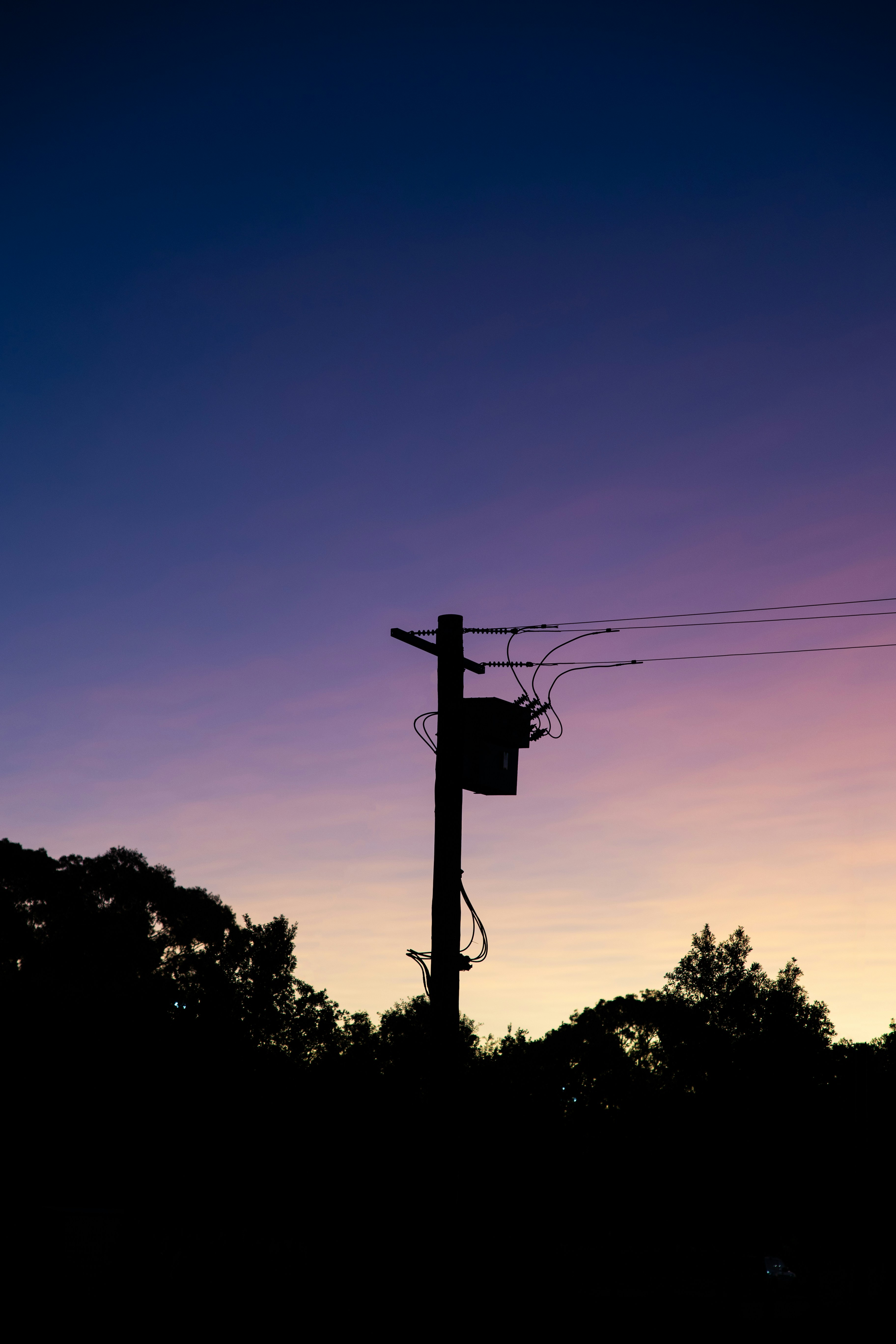 Silhouette of a utility pole against a twilight sky.