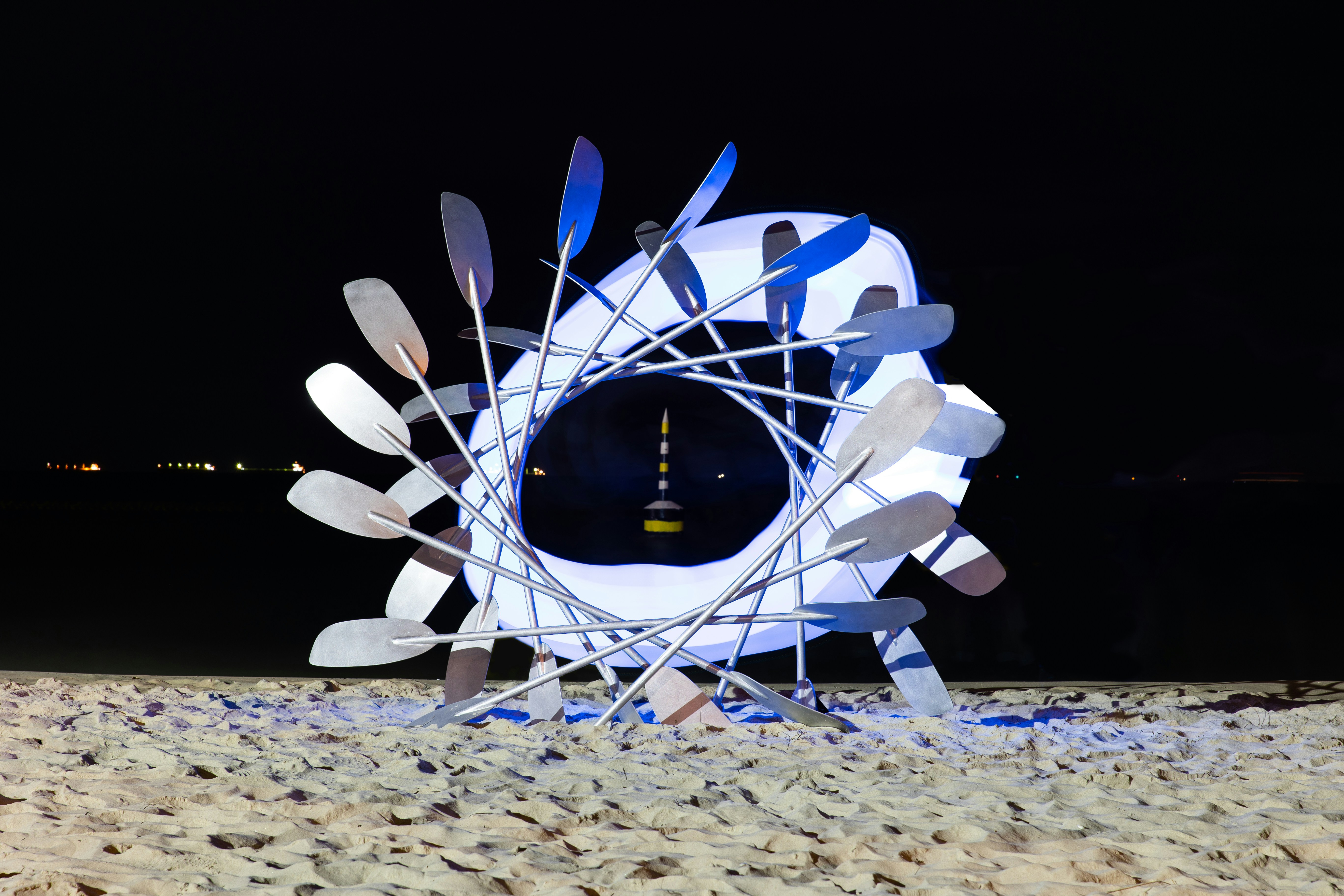 Sculpture with paddles on a beach at night