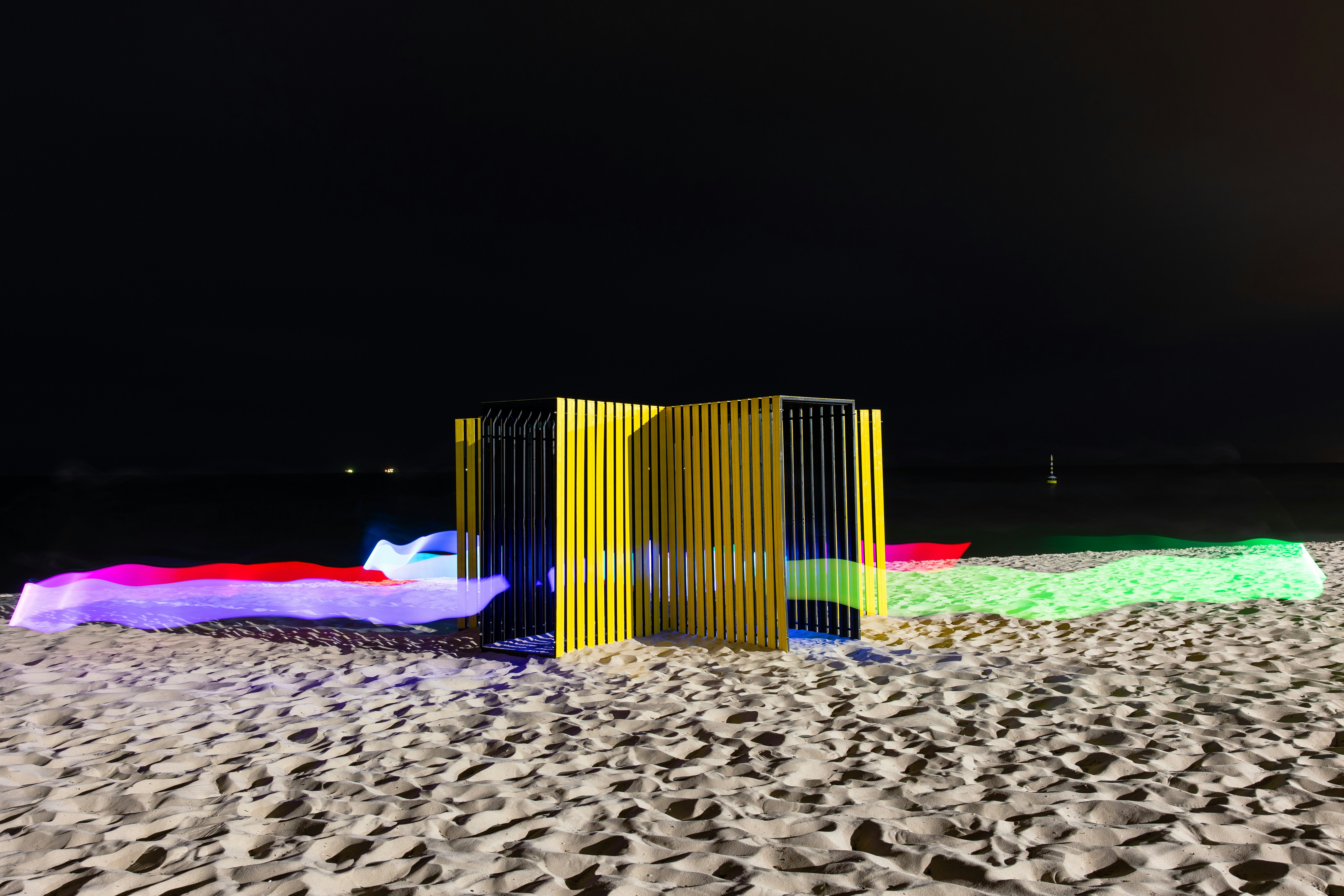 Yellow structure on beach with colorful lights at night