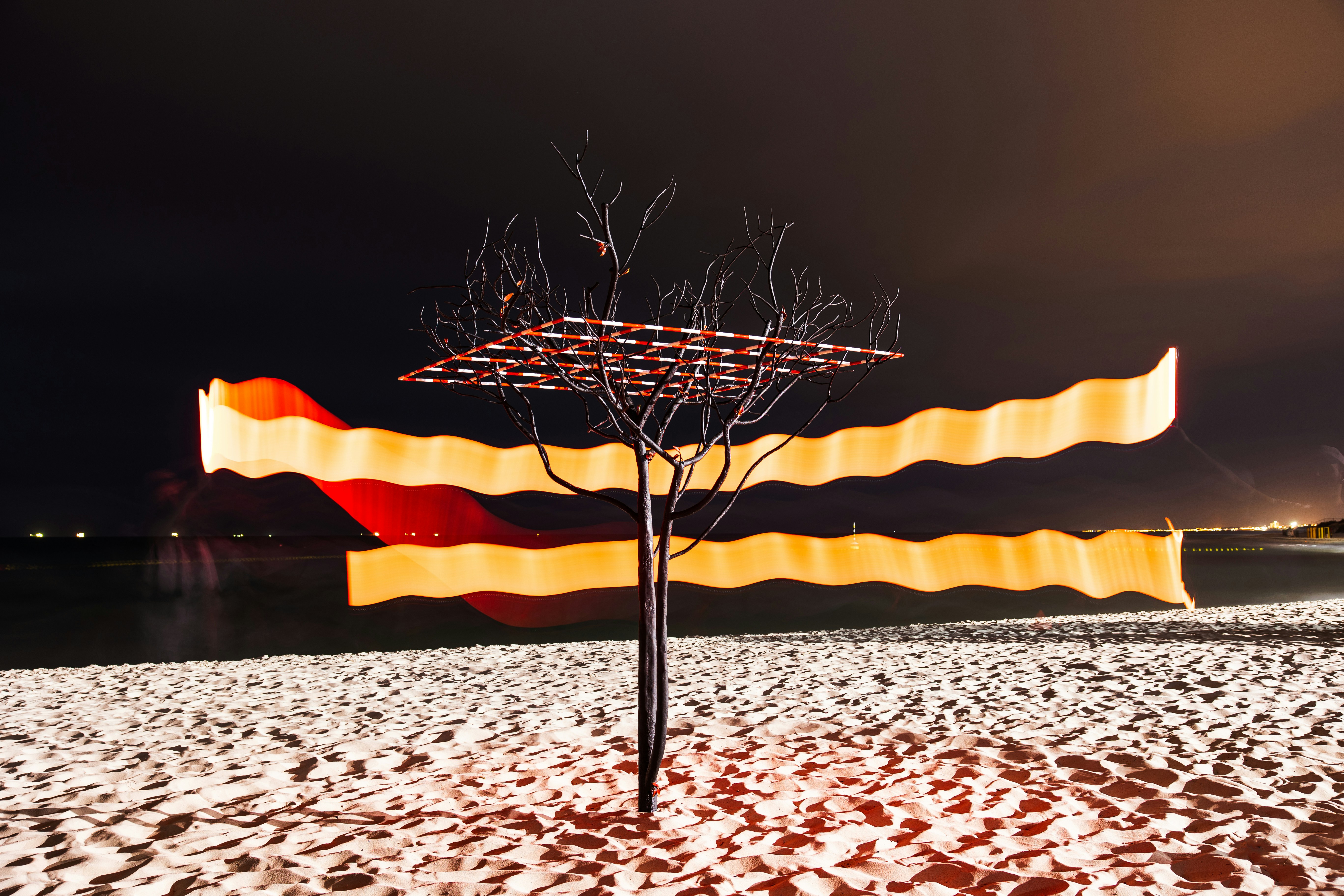 Sculpture on a beach at night with light streaks