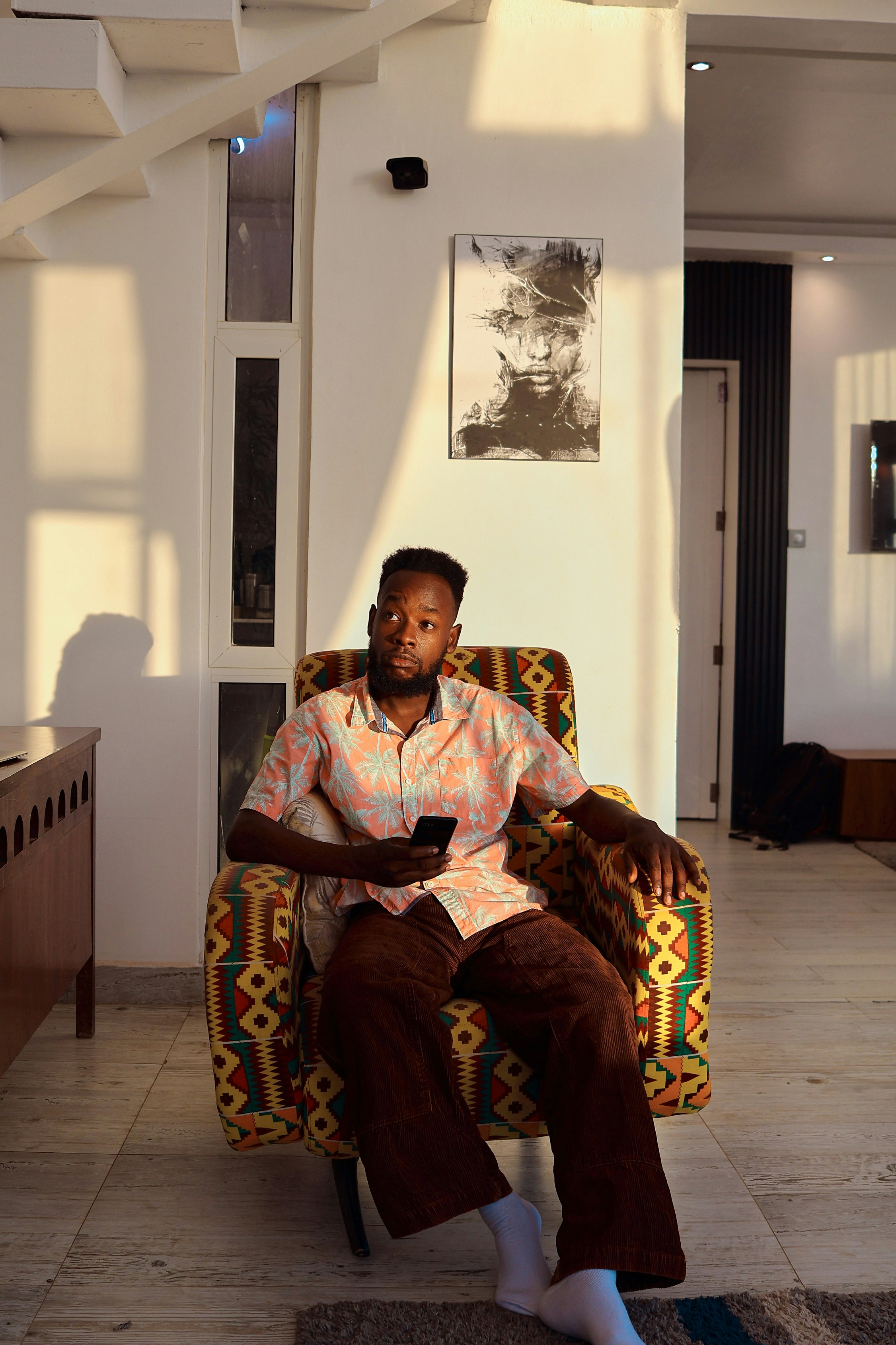 Man sitting in a colorful armchair holding a phone