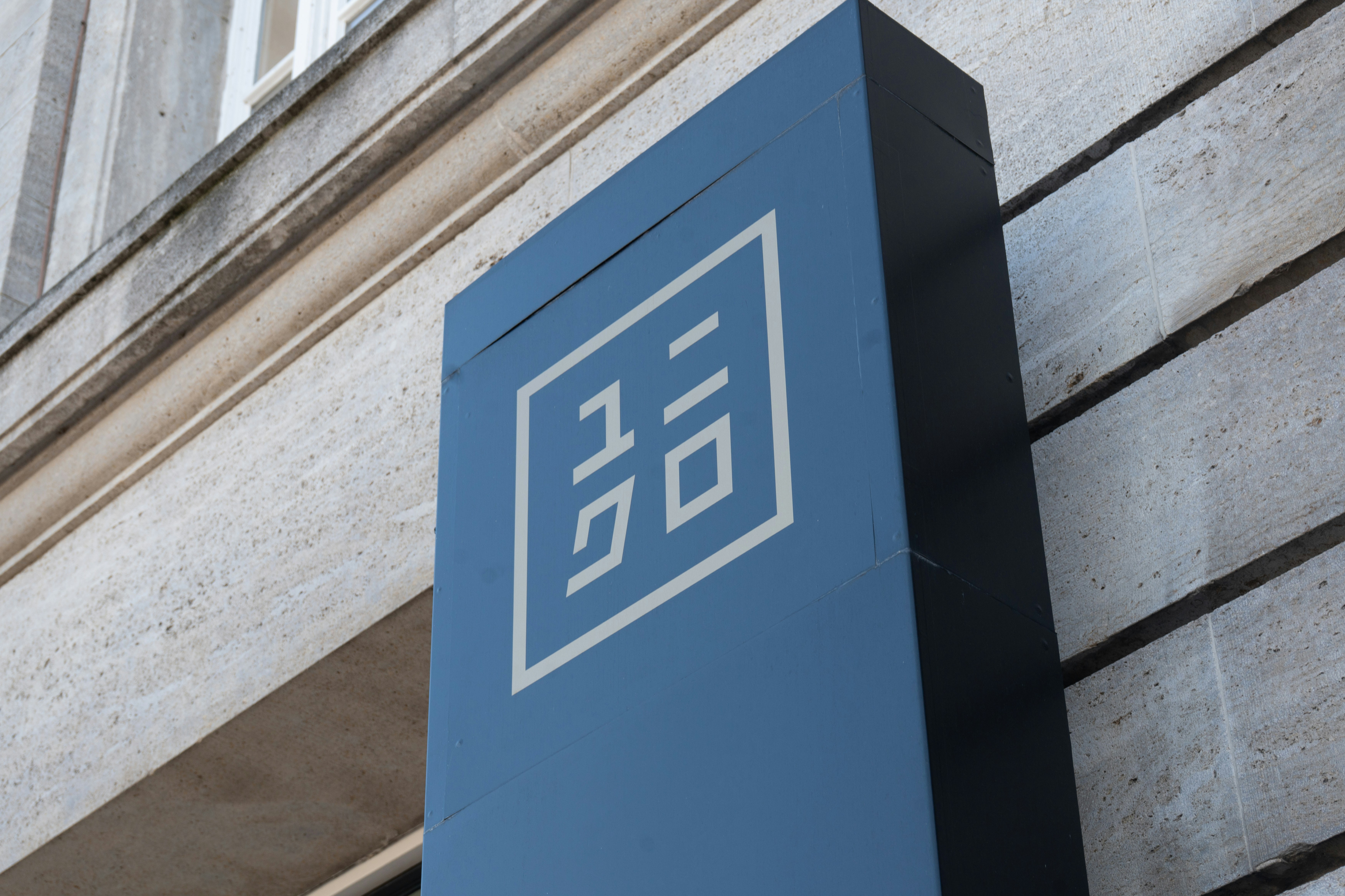 建物に白い幾何学的ロゴが入った青い看板