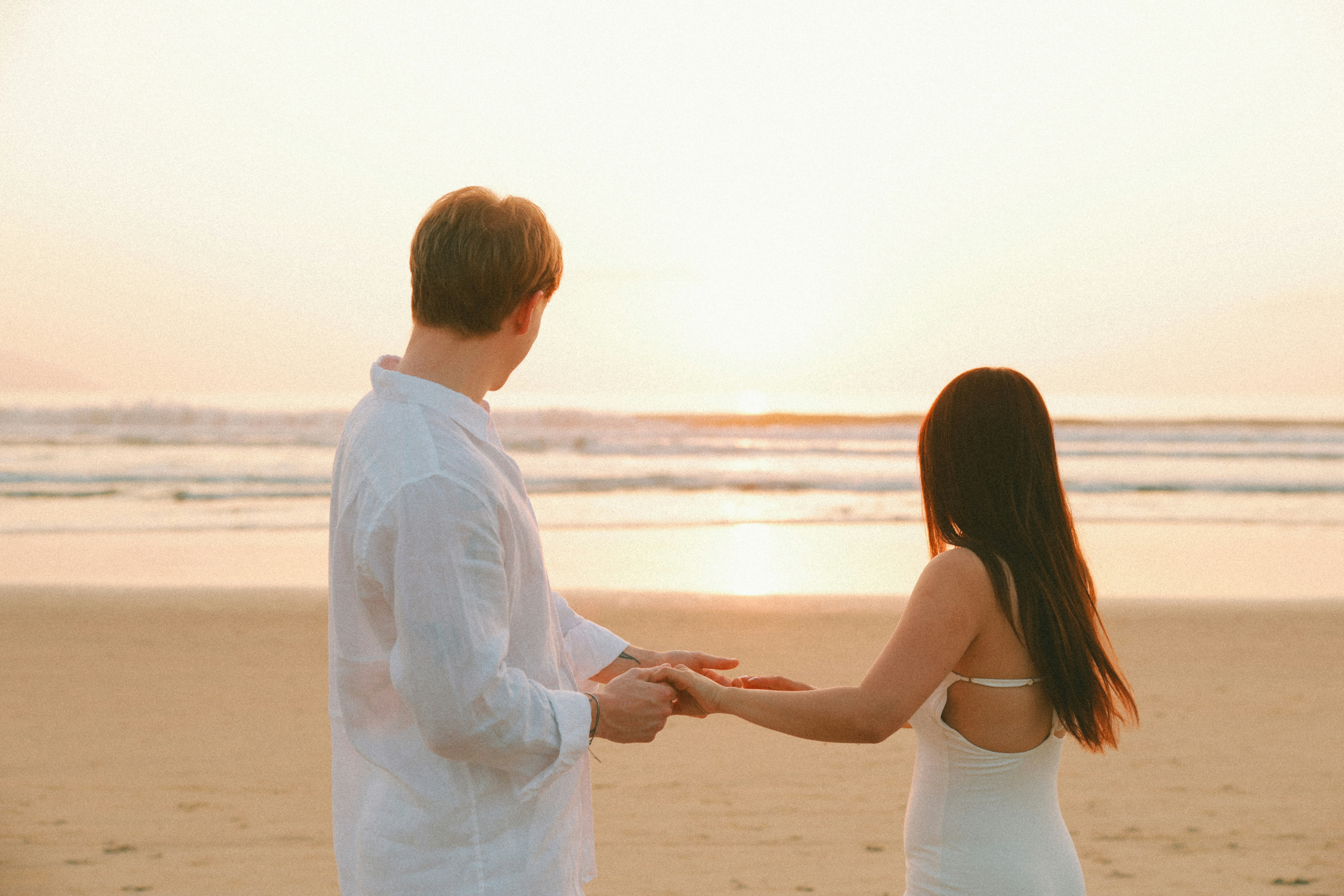 Couple holding hands on a beach at sunset