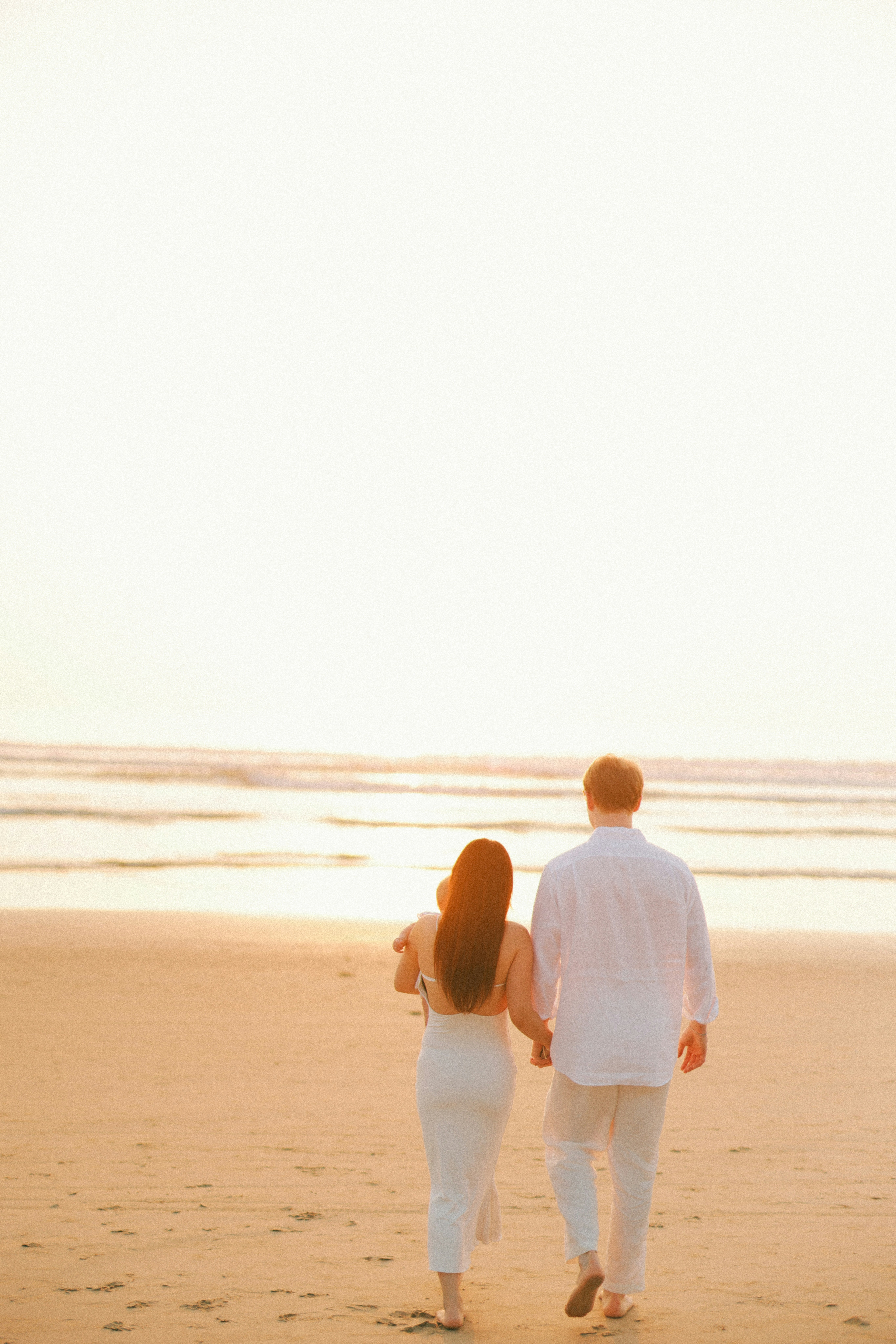Couple holding hands walking on a beach at sunset