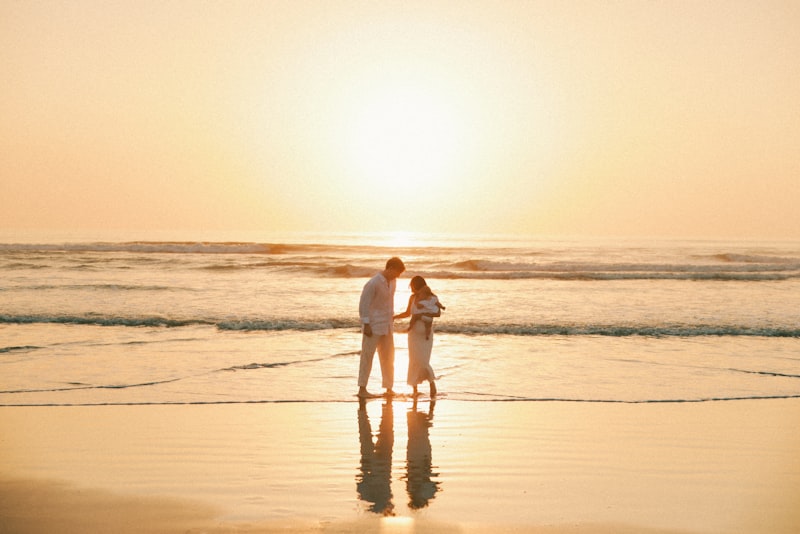 Family with baby on beach at golden hour in white outfits
