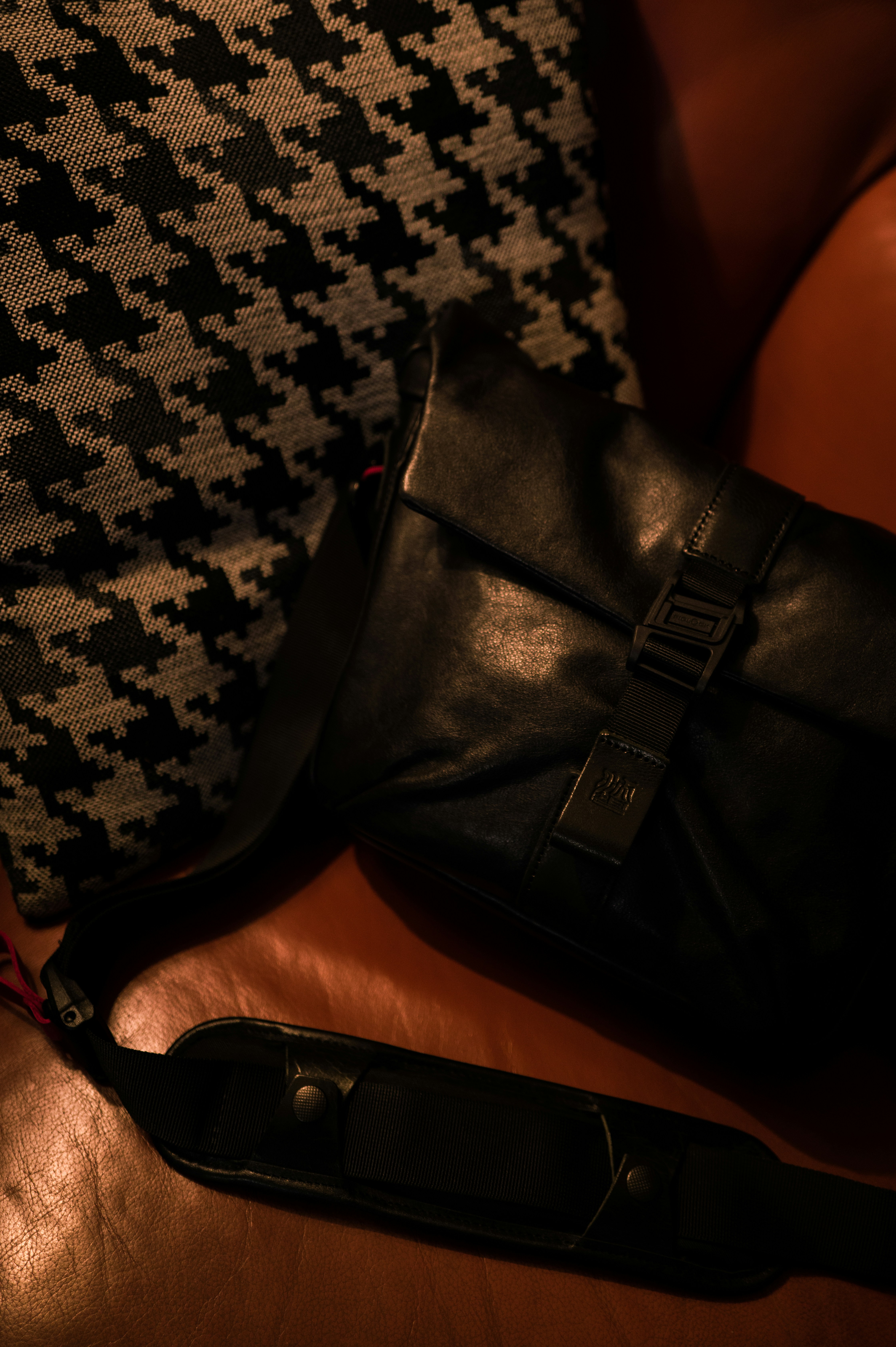 Un bolso de cuero negro descansa sobre un sofá de cuero marrón.