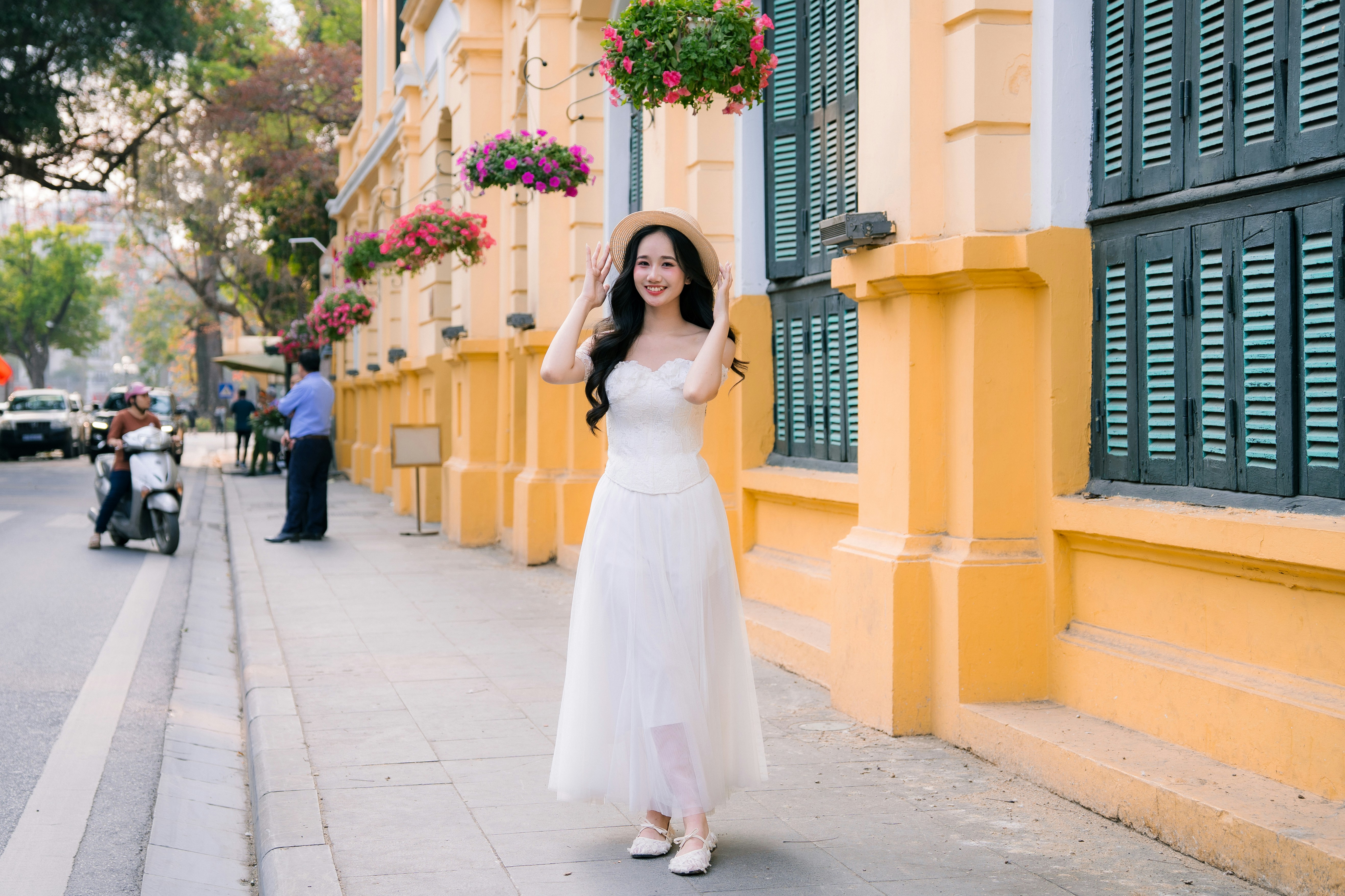 A woman in a white dress walks on a street.