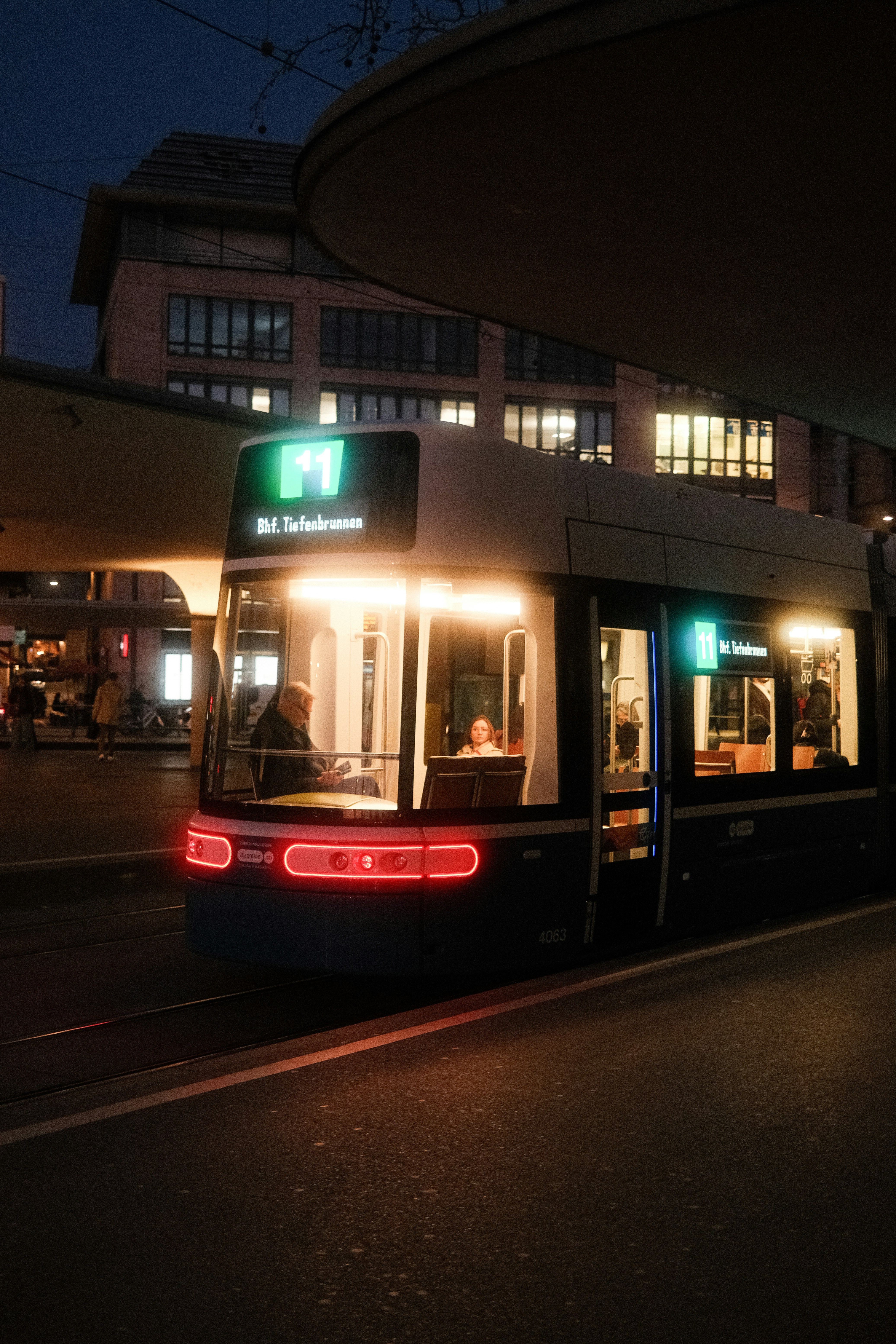 Photo of A tram at night with illuminated windows and lights. by Joel Ambass