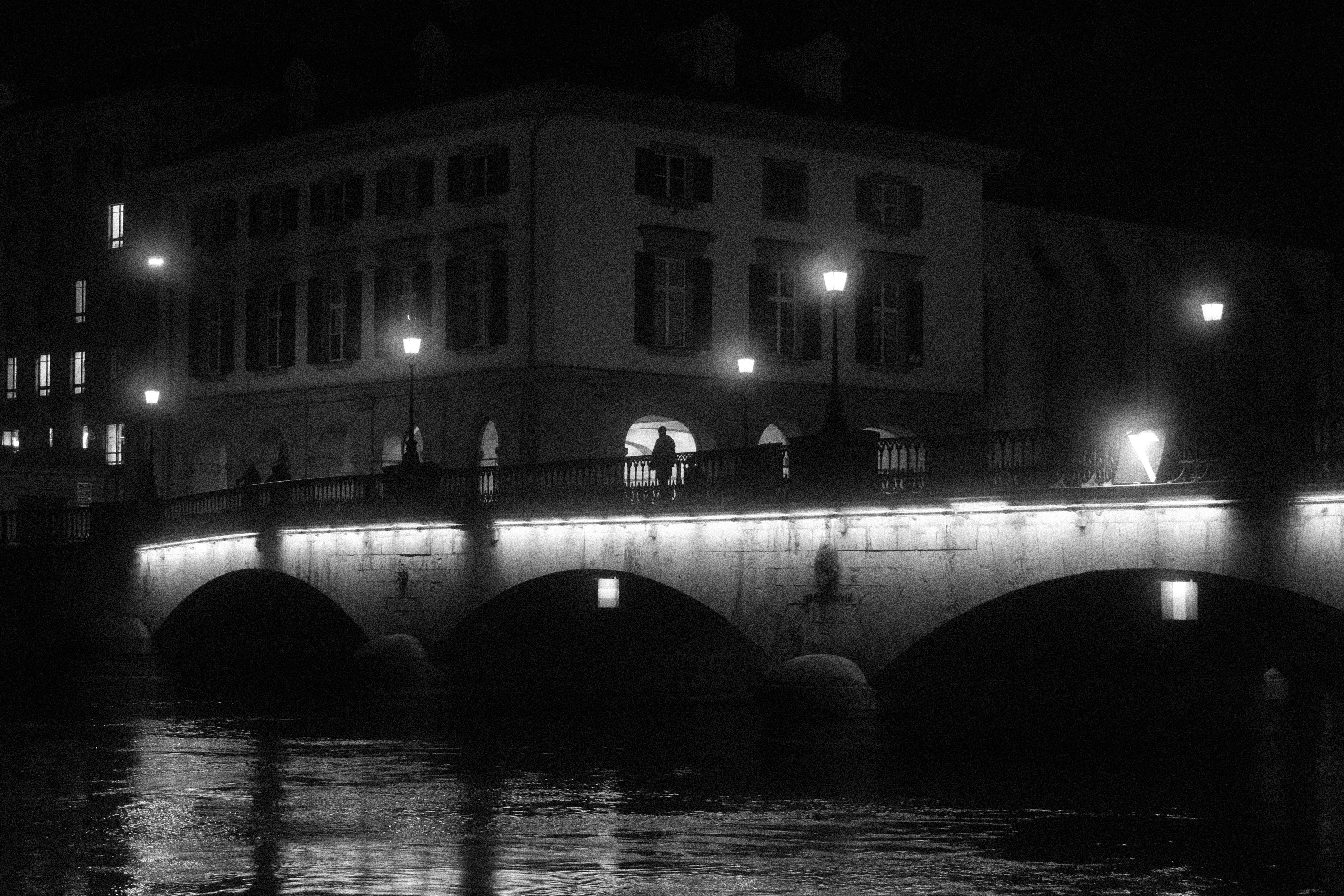 Una figura solitaria está de pie en un puente por la noche.