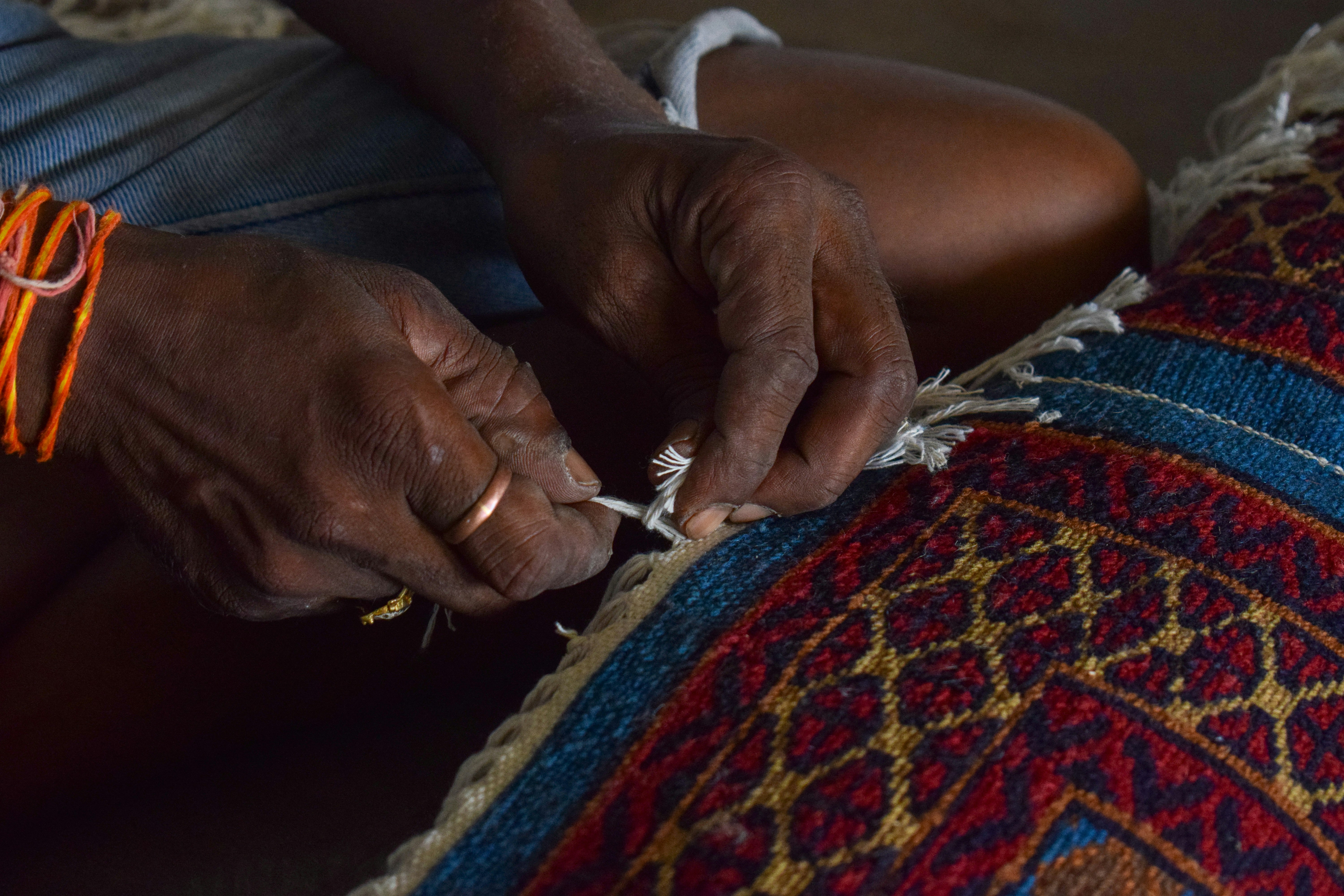 Hands of a person weaving a colorful rug