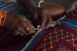 Hands of a person weaving a colorful rug- Kanha Universal Export-Exporter In India