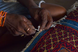 Hands of a person weaving a colorful rug- Kanha Universal Export-Exporter In India