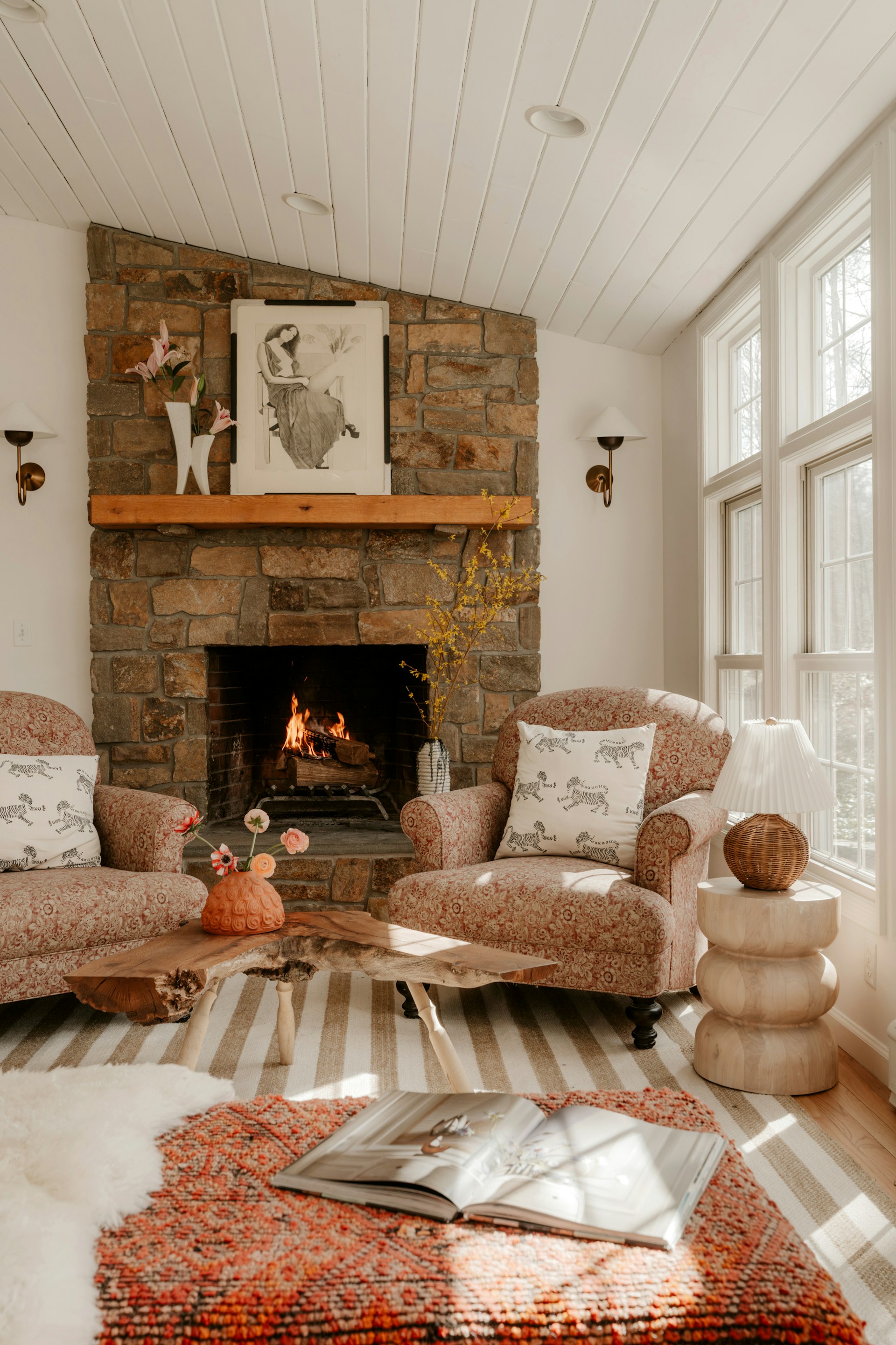 Bright cozy living room with a stone fireplace and warm neutral pillows, a soft fall color palette