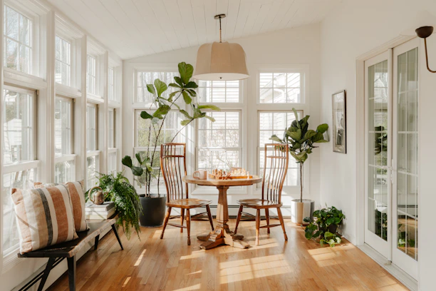 Bright sunroom with plants and dining table.