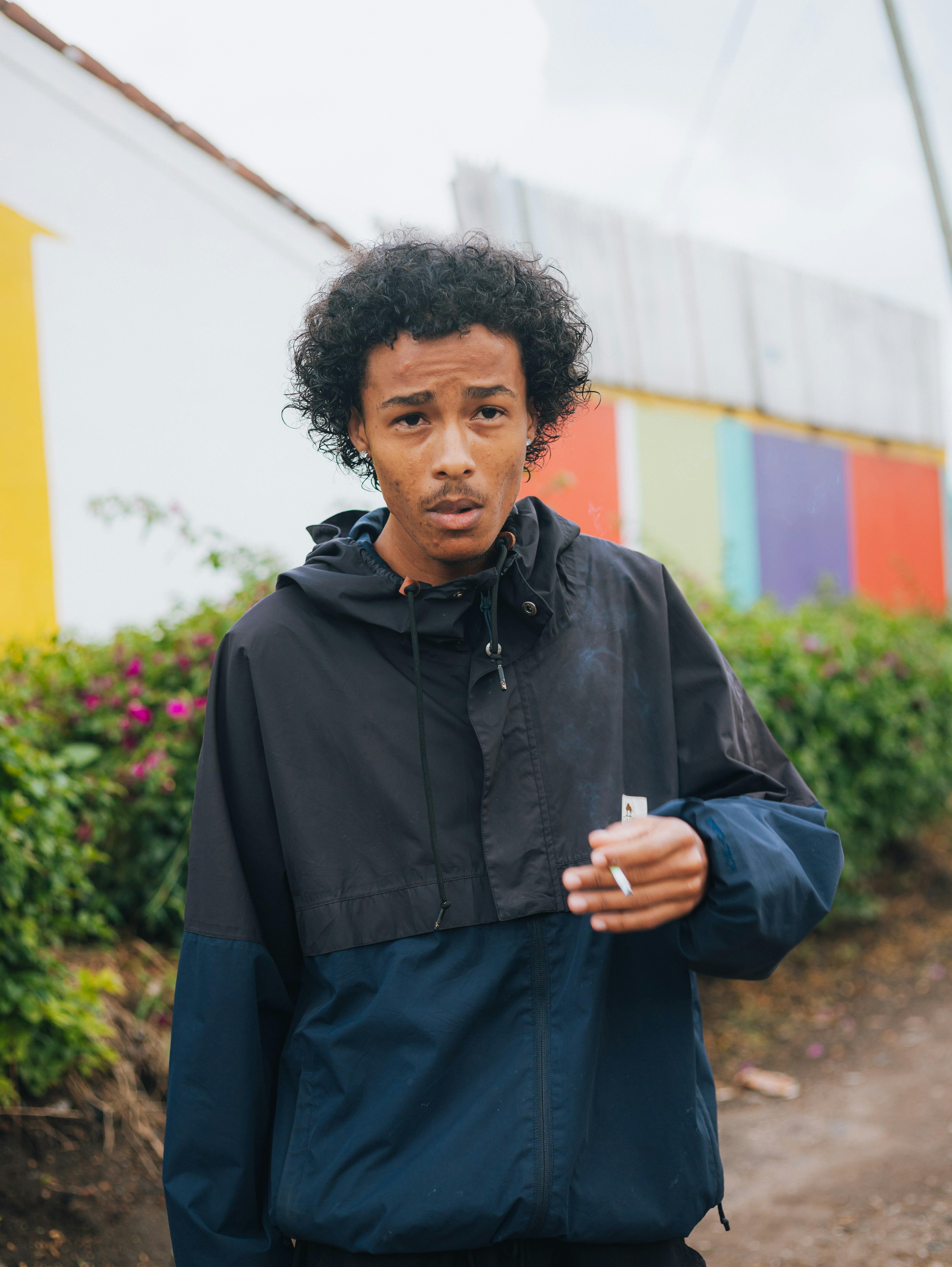 Young man with curly hair smoking outdoors