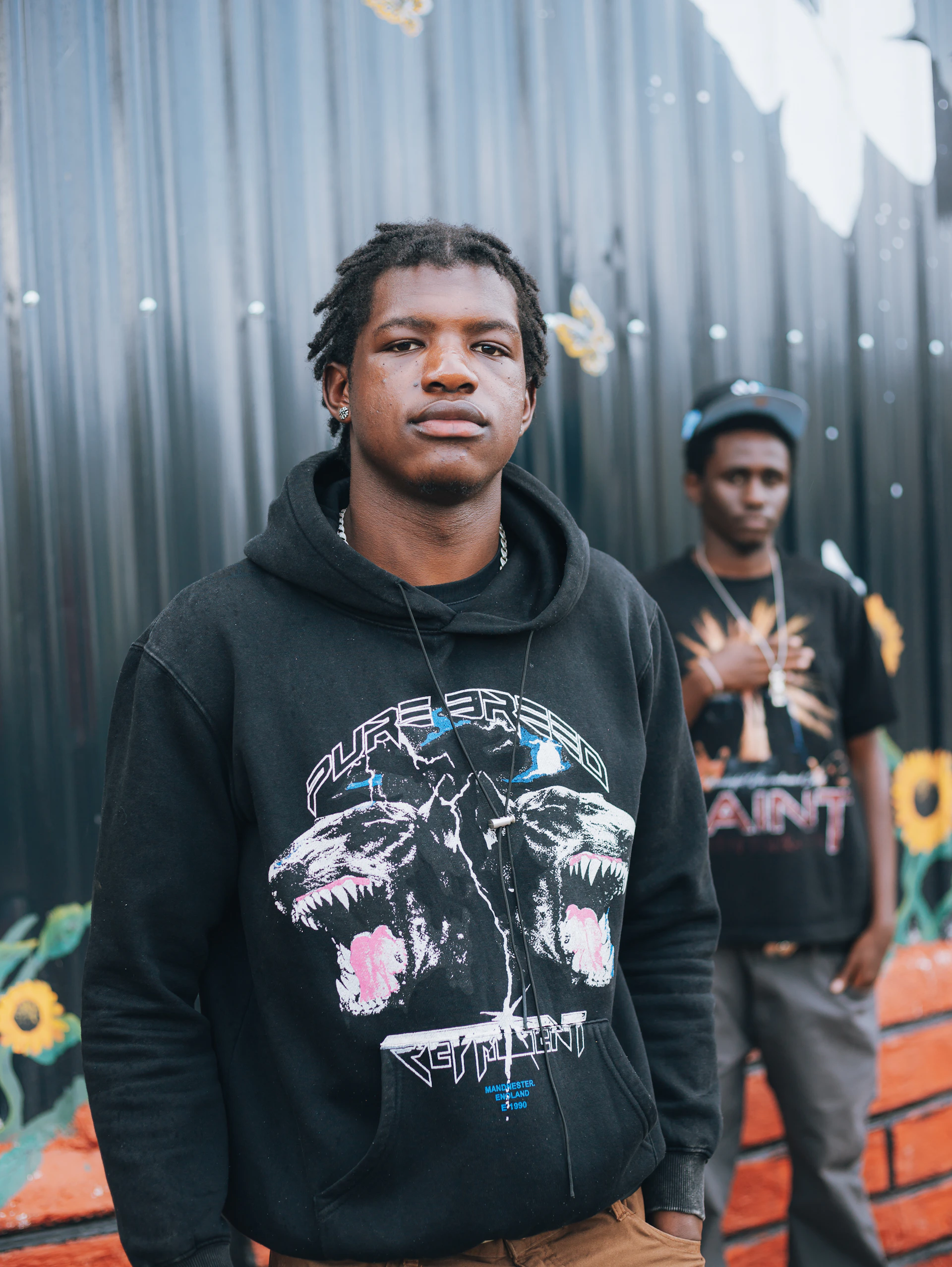 Two young men standing in front of a mural