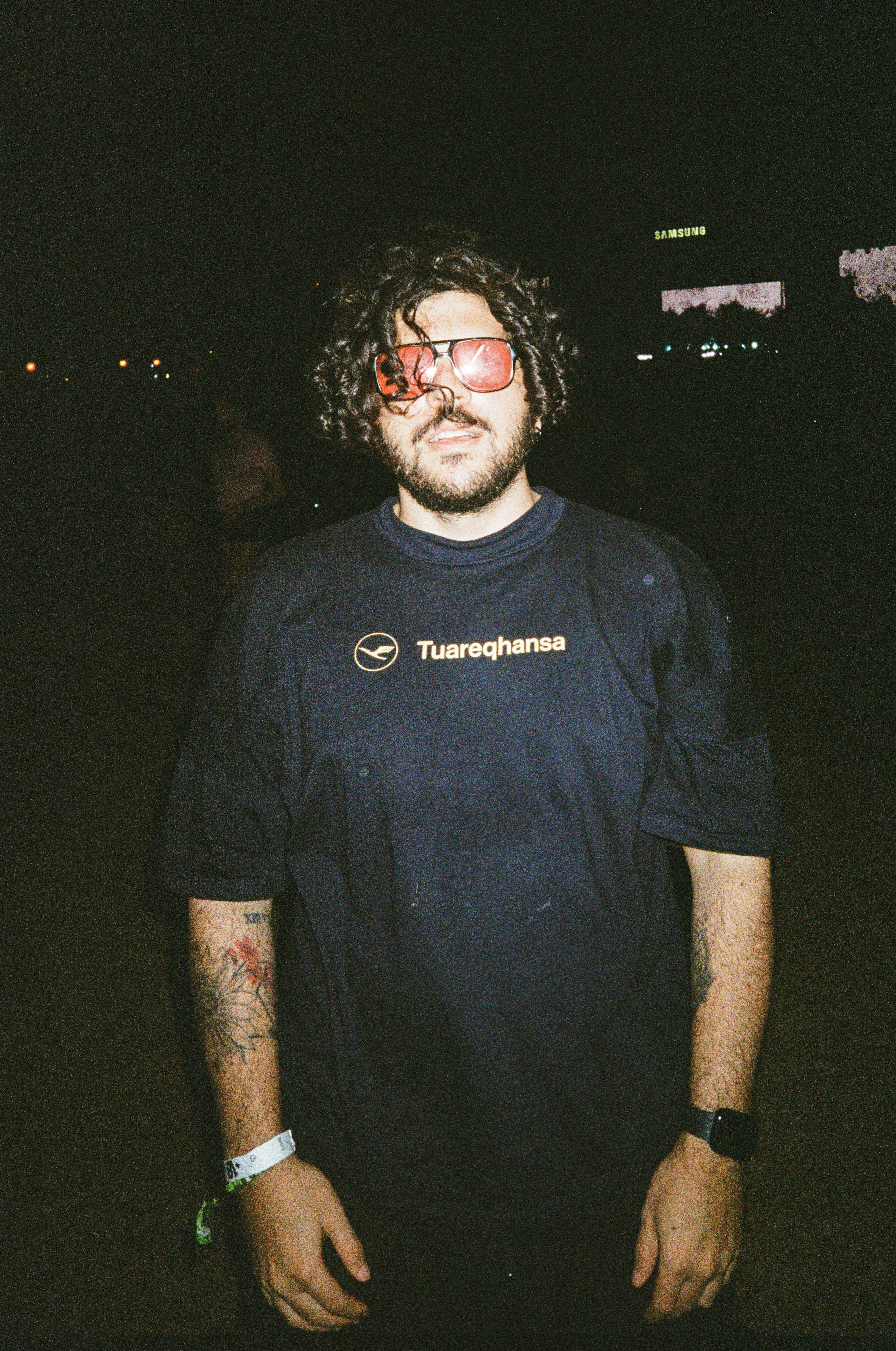 Pria dengan rambut keriting dan kacamata hitam di malam hari