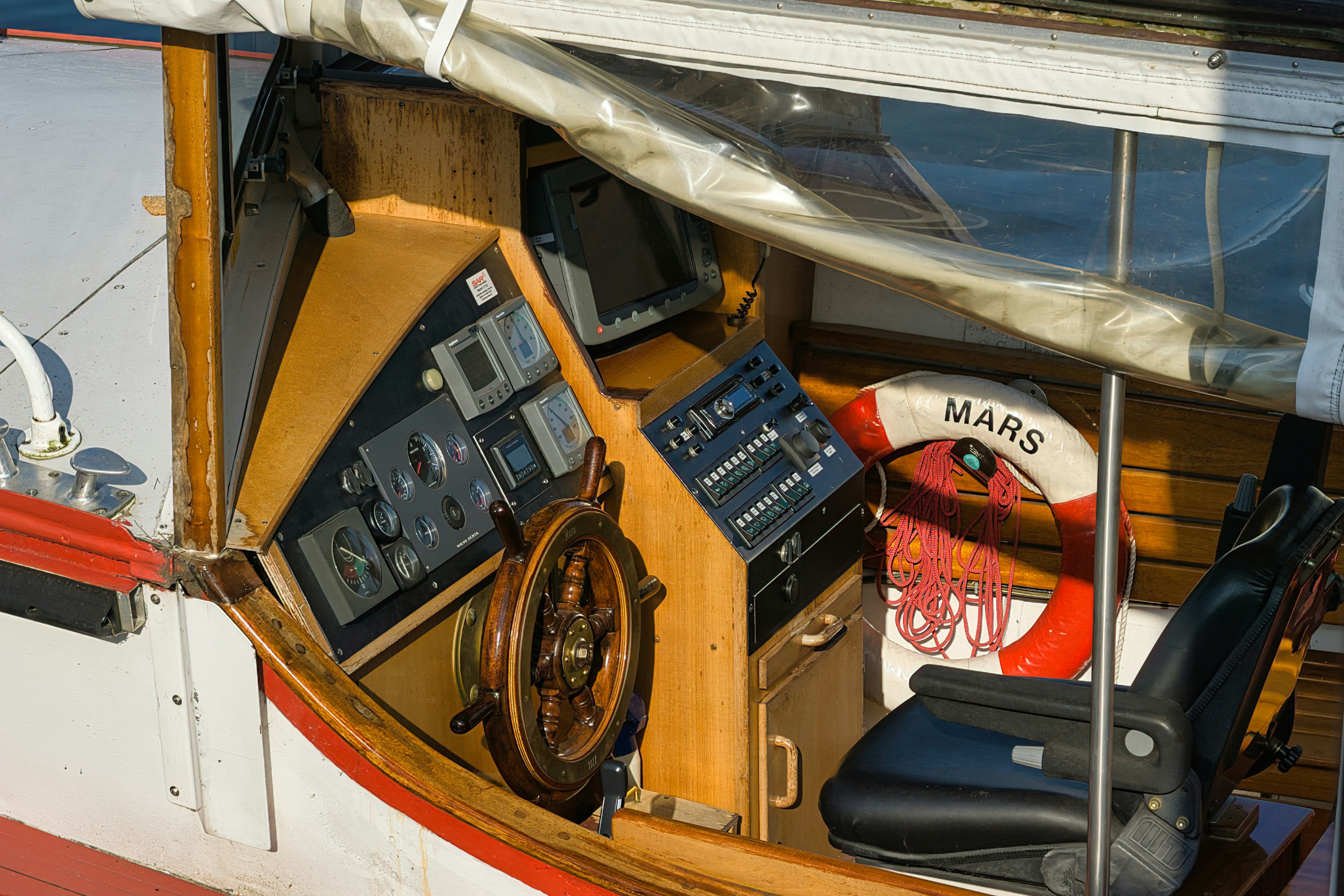 Wooden ship's wheel and control panel on a boat.