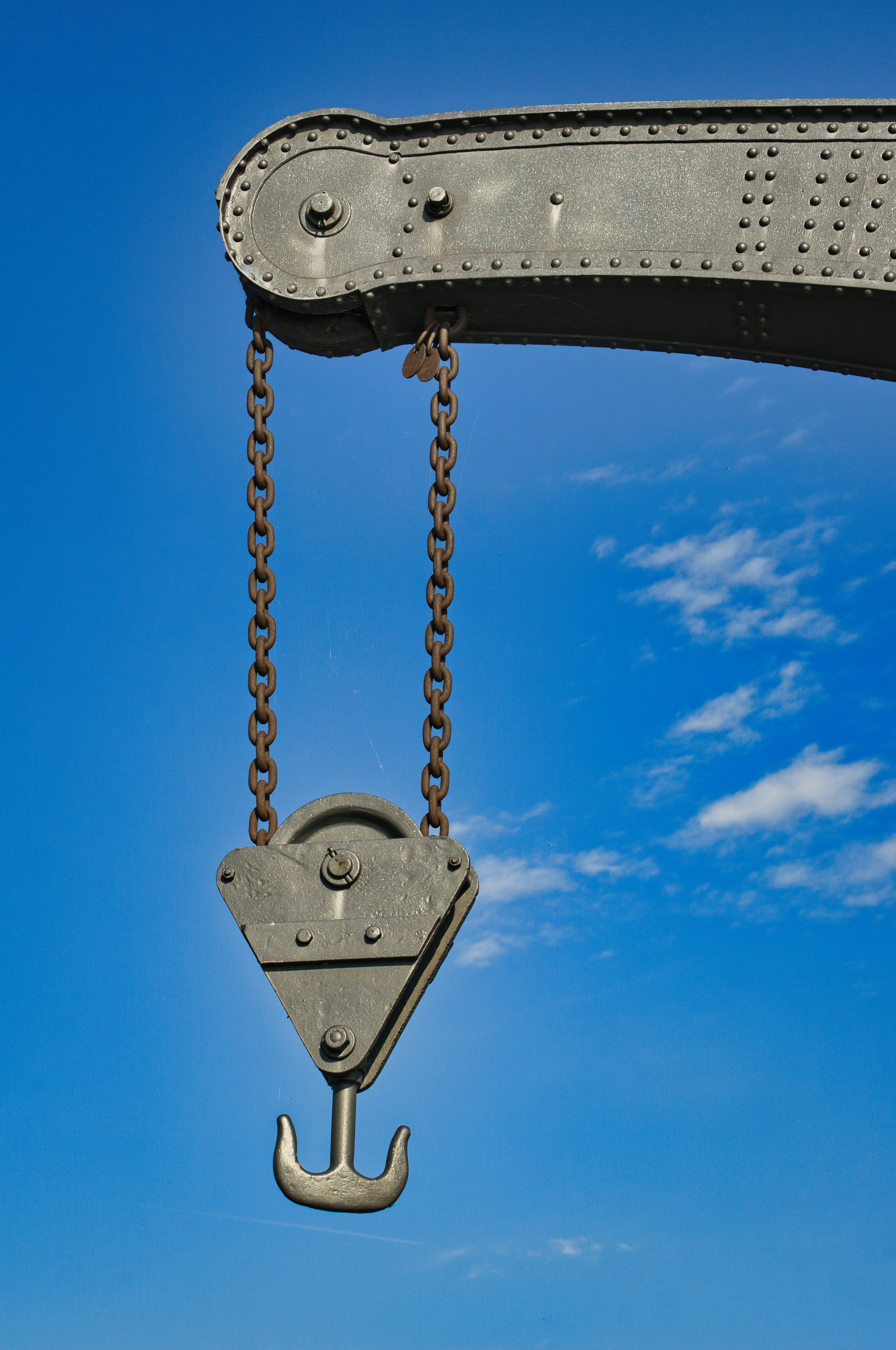Kranhaken und Ketten gegen blauen Himmel.