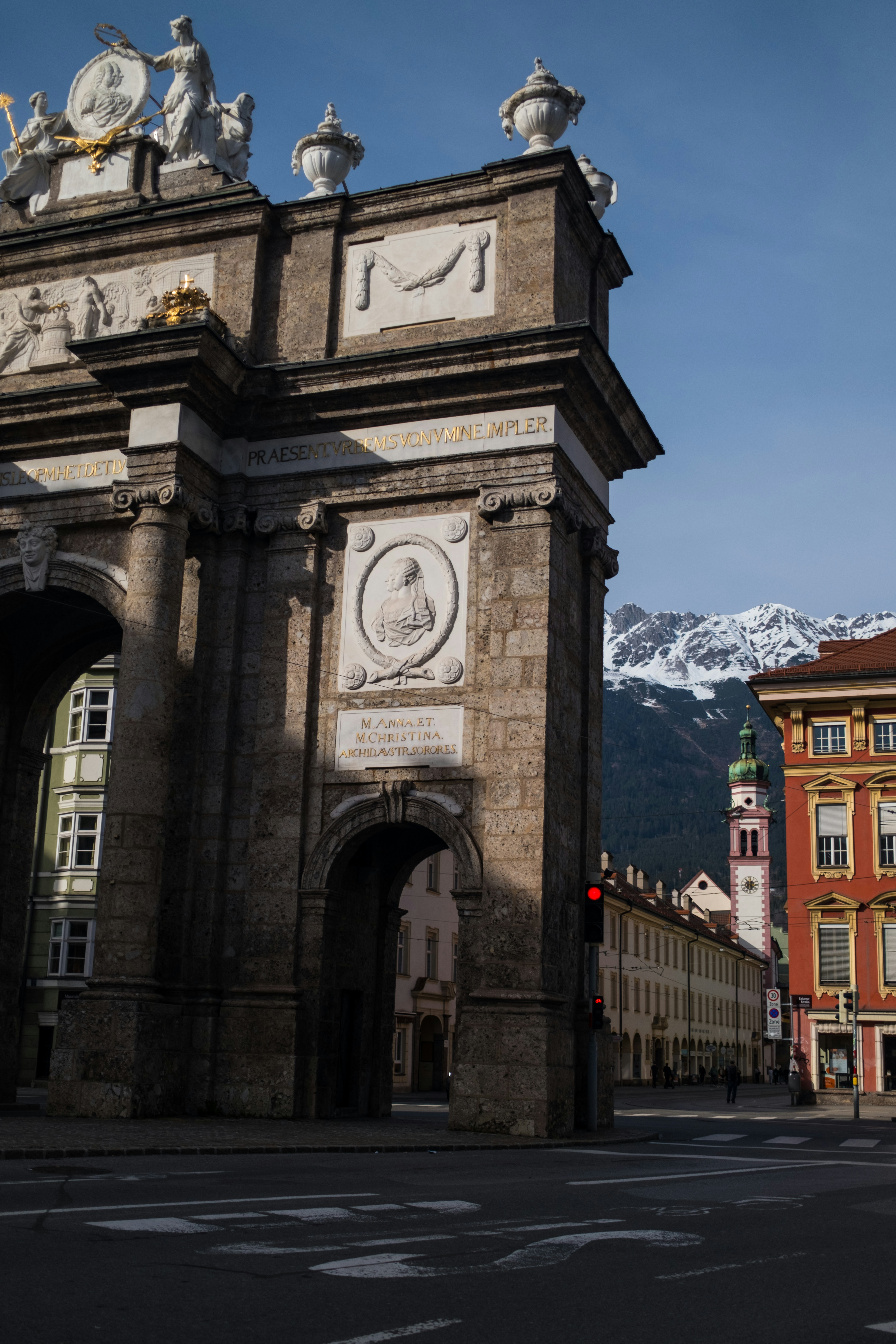Triumphal arch with snow-capped mountains in background.