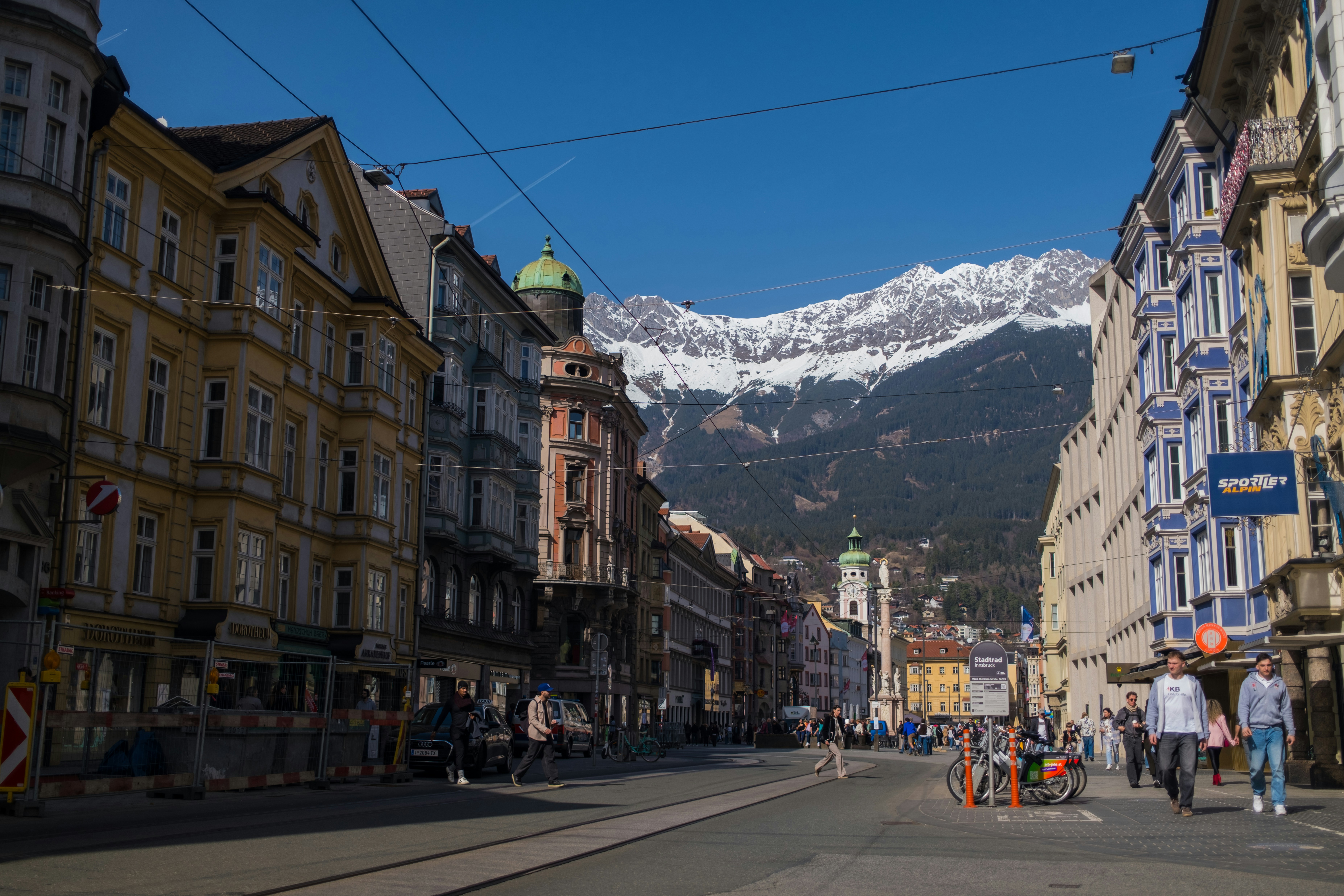 City street with buildings and snow-capped mountains in background