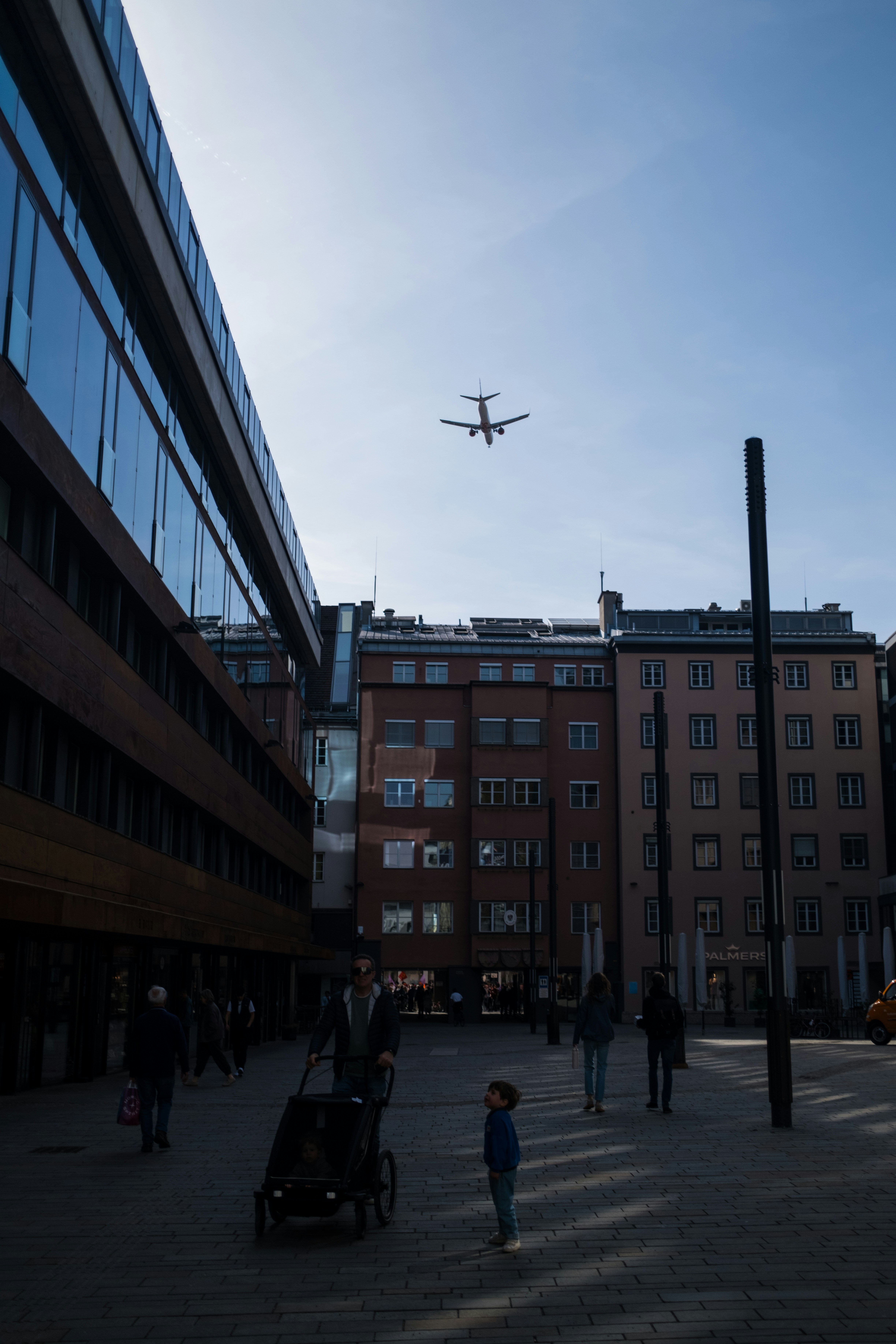 Airplane flying over city buildings with people walking